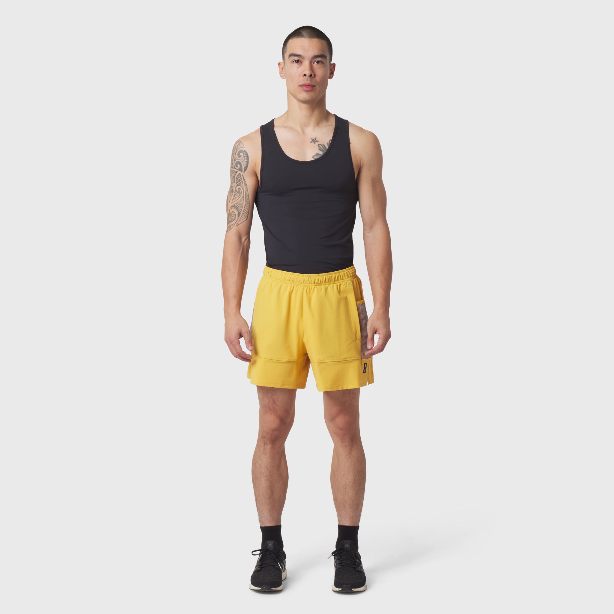 Black LYCRA® ADAPTIV baselayer tank on model with yellow shorts, front view