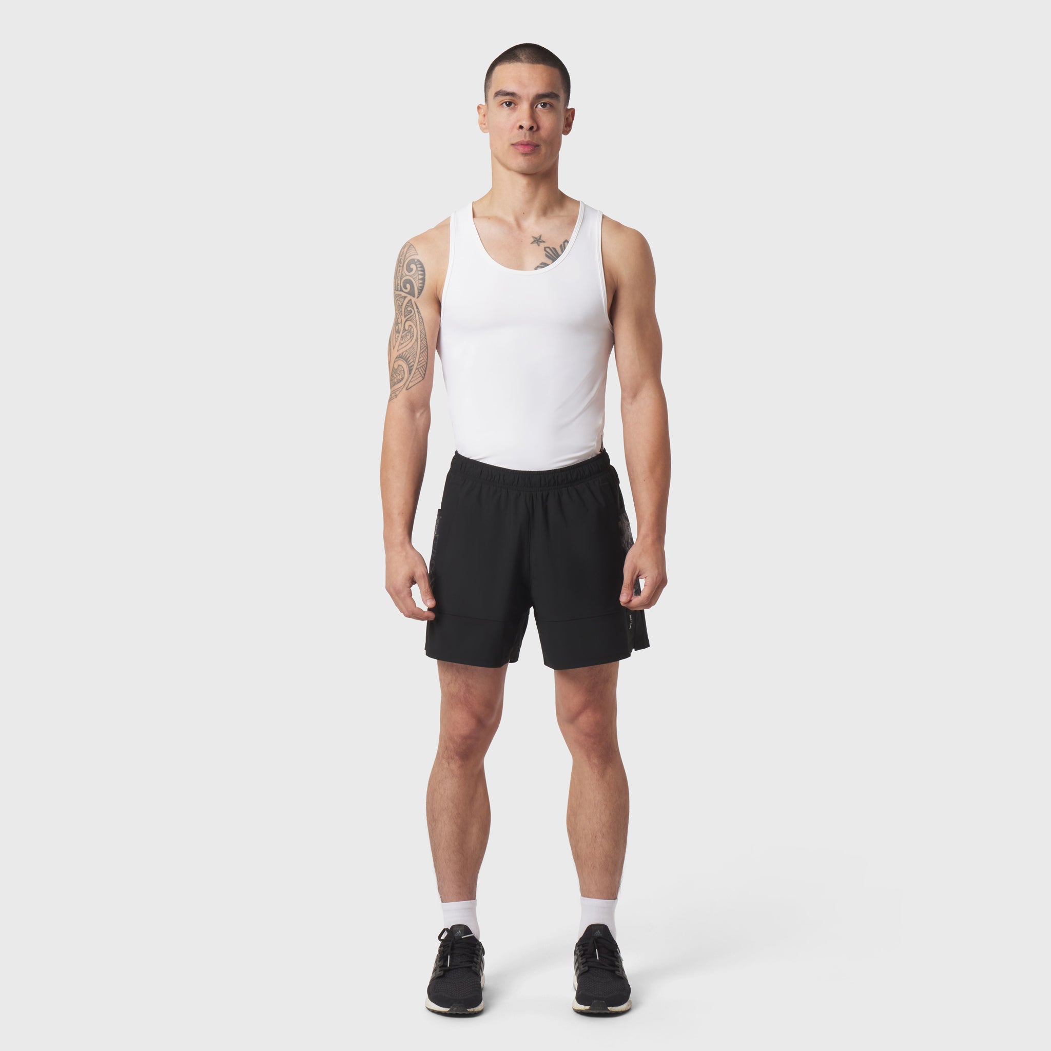 White LYCRA® ADAPTIV Baselayer Tank on model with black shorts, front view