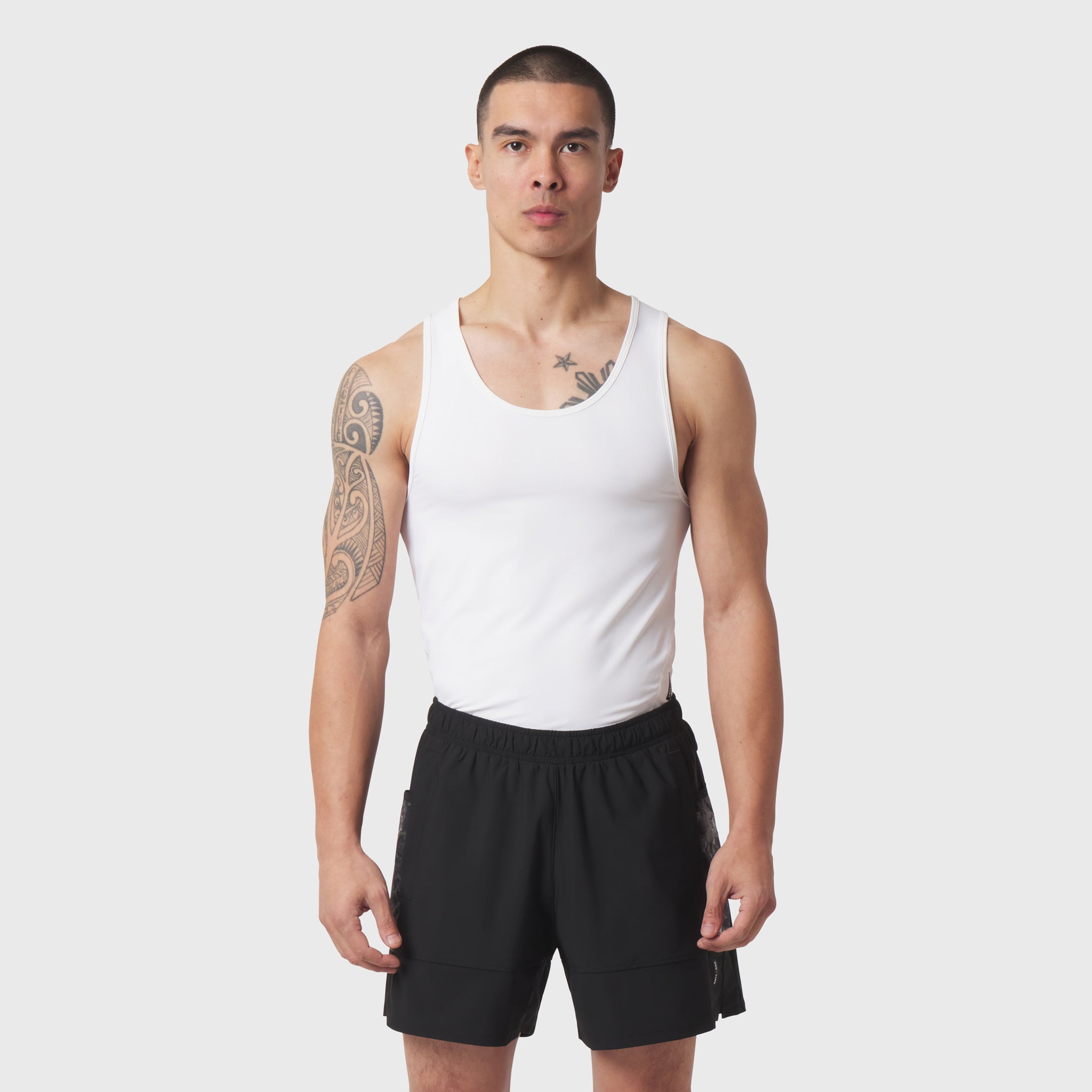 White LYCRA® ADAPTIV Baselayer Tank worn with black shorts, front view on model