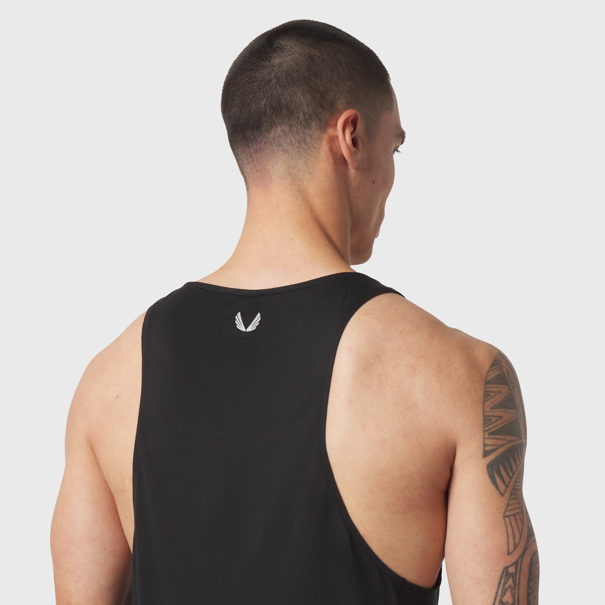 Black Polartec Delta singlet worn by model, back view showing logo and tattoo