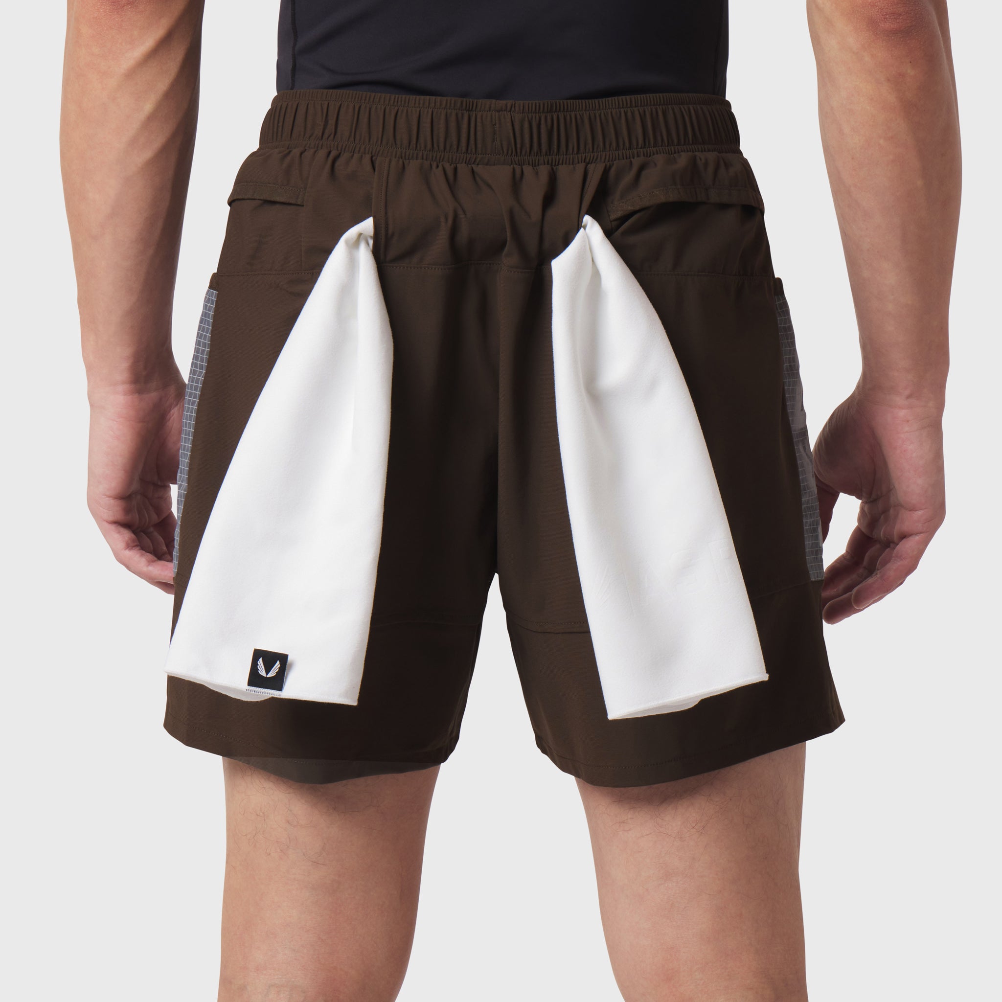 Tetra-Lite Adventure Short in dark earth worn by model, back view with white towels