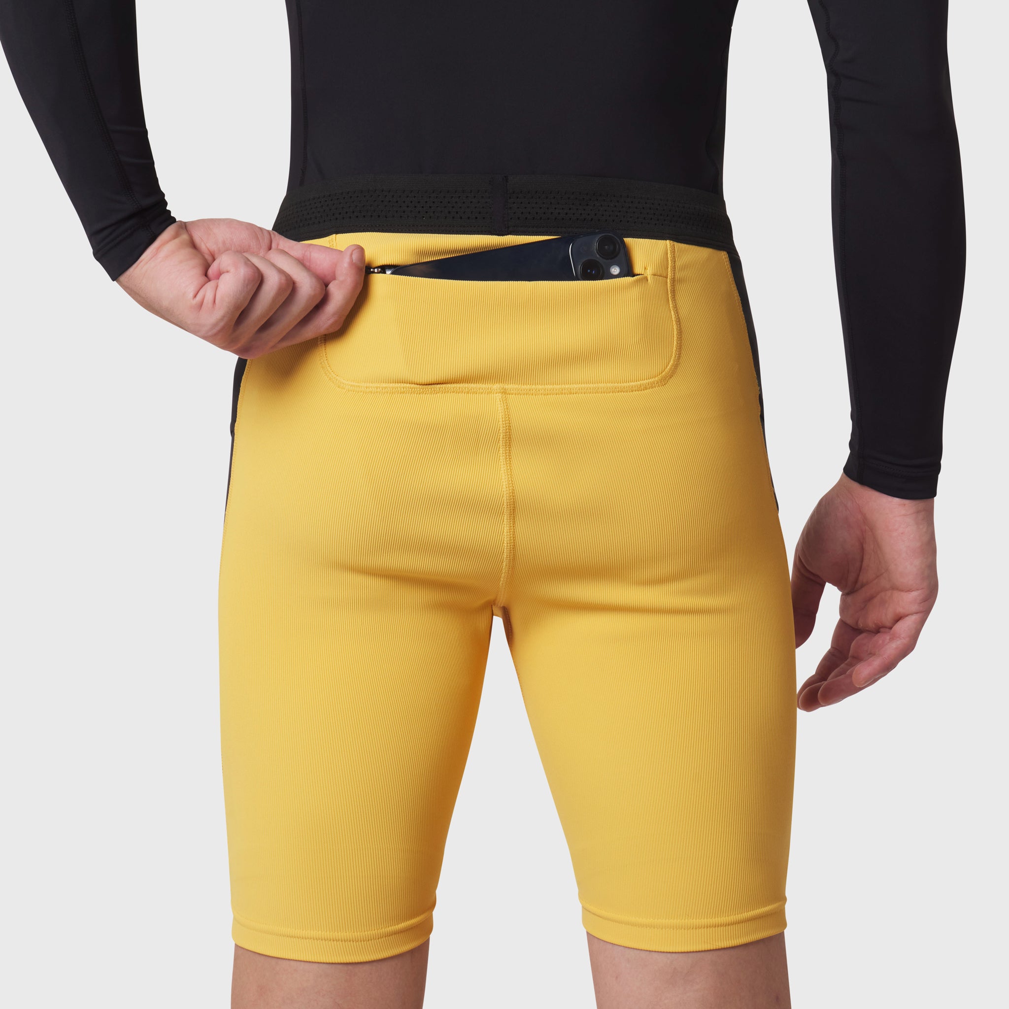 Lycra Ribbed Run Half-Tight in amber yellow worn by model, front view with hand in pocket