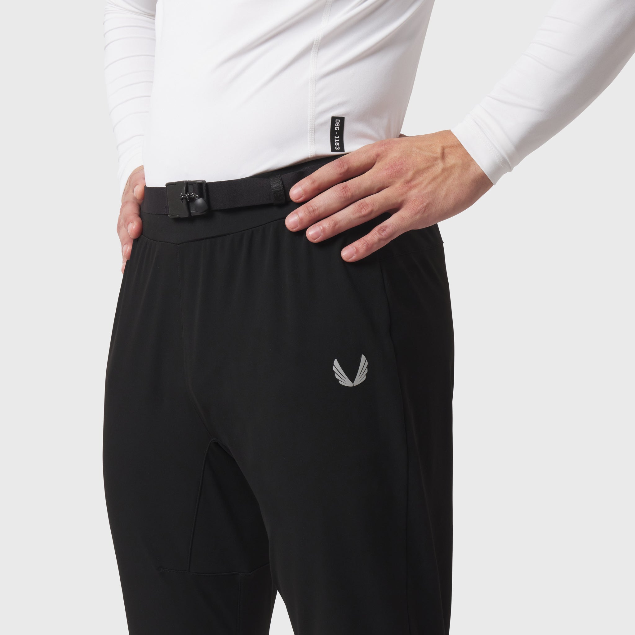 Black hybrid belt-pack run jogger worn by model, waist detail view with white long-sleeve shirt