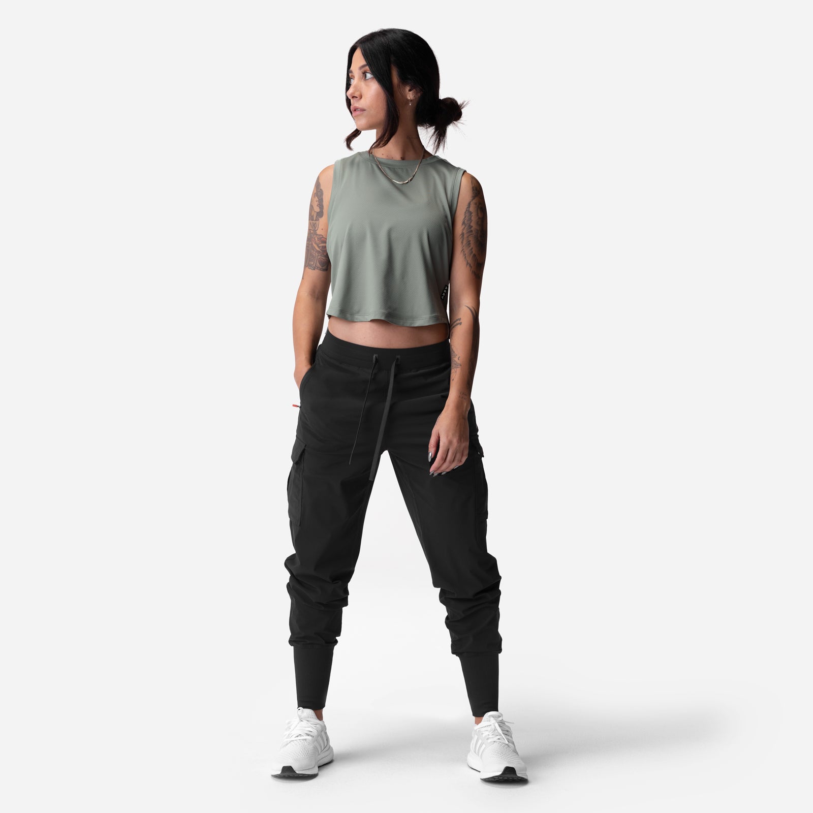 Sage cropped training tank worn with black cargo joggers and white sneakers, front view