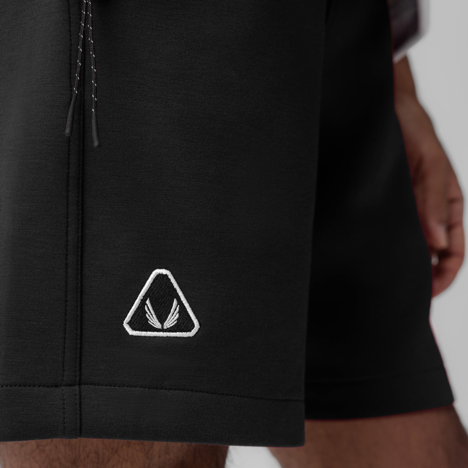 Dri-Core Training Short in black worn by model, side view showing triangle logo detail