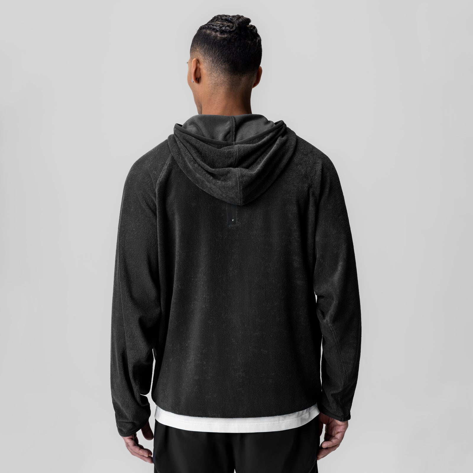 Black towel terry reversible hoodie worn by model, back view