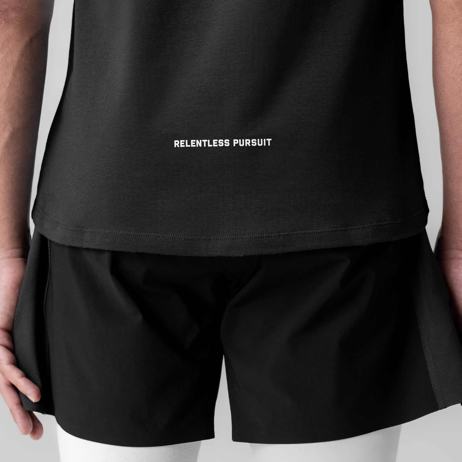 Creora® Cotton Modal Cutoff Tank in black with 'Relentless Pursuit' text, worn by model, back view