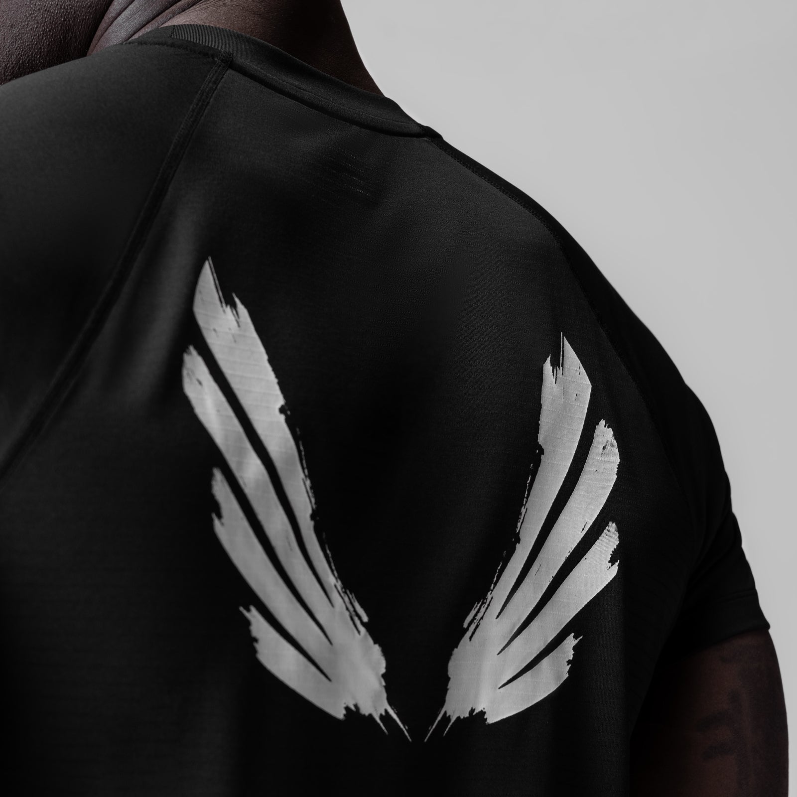 Black fitted tee with white brush wings graphic on back, worn by model