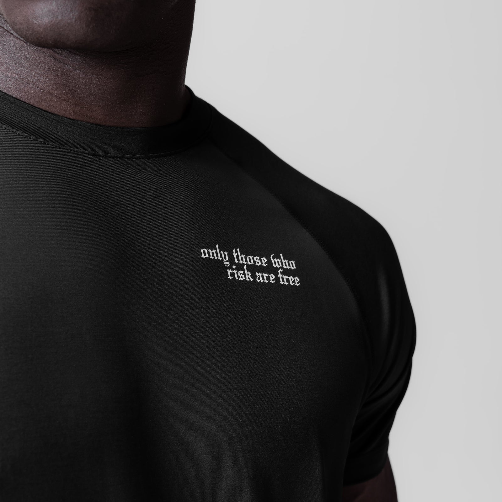 Black fitted tee with 'only those who risk are free' text, worn by model, front view