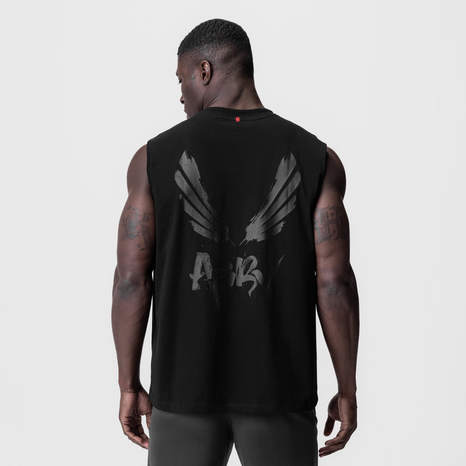 Black Tech Essential Relaxed Cutoff tank with gray brush wings graphic, back view on model