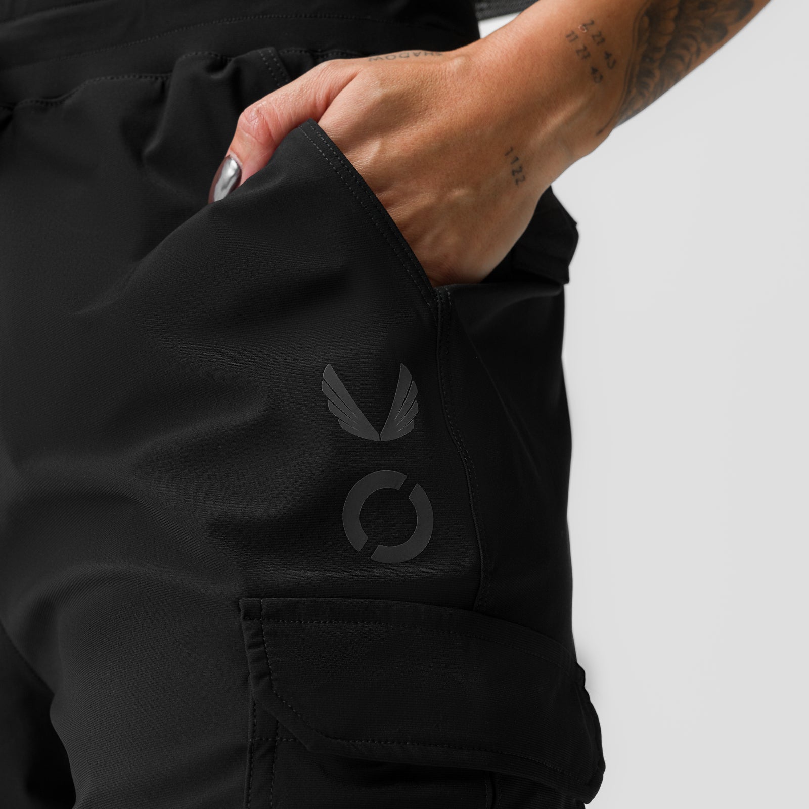 Black high-rib cargo jogger with hand in pocket, showing logo detail
