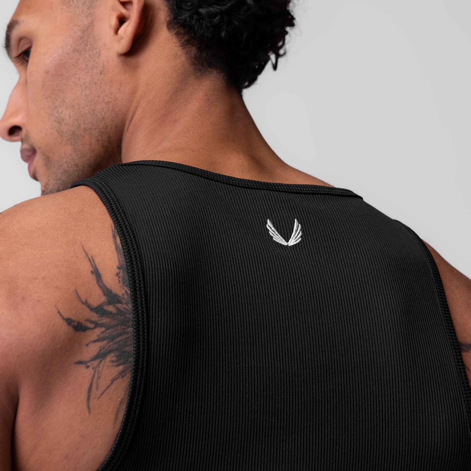 Black Creora® Tech Ribbed Tank worn by model, rear view showing logo detail