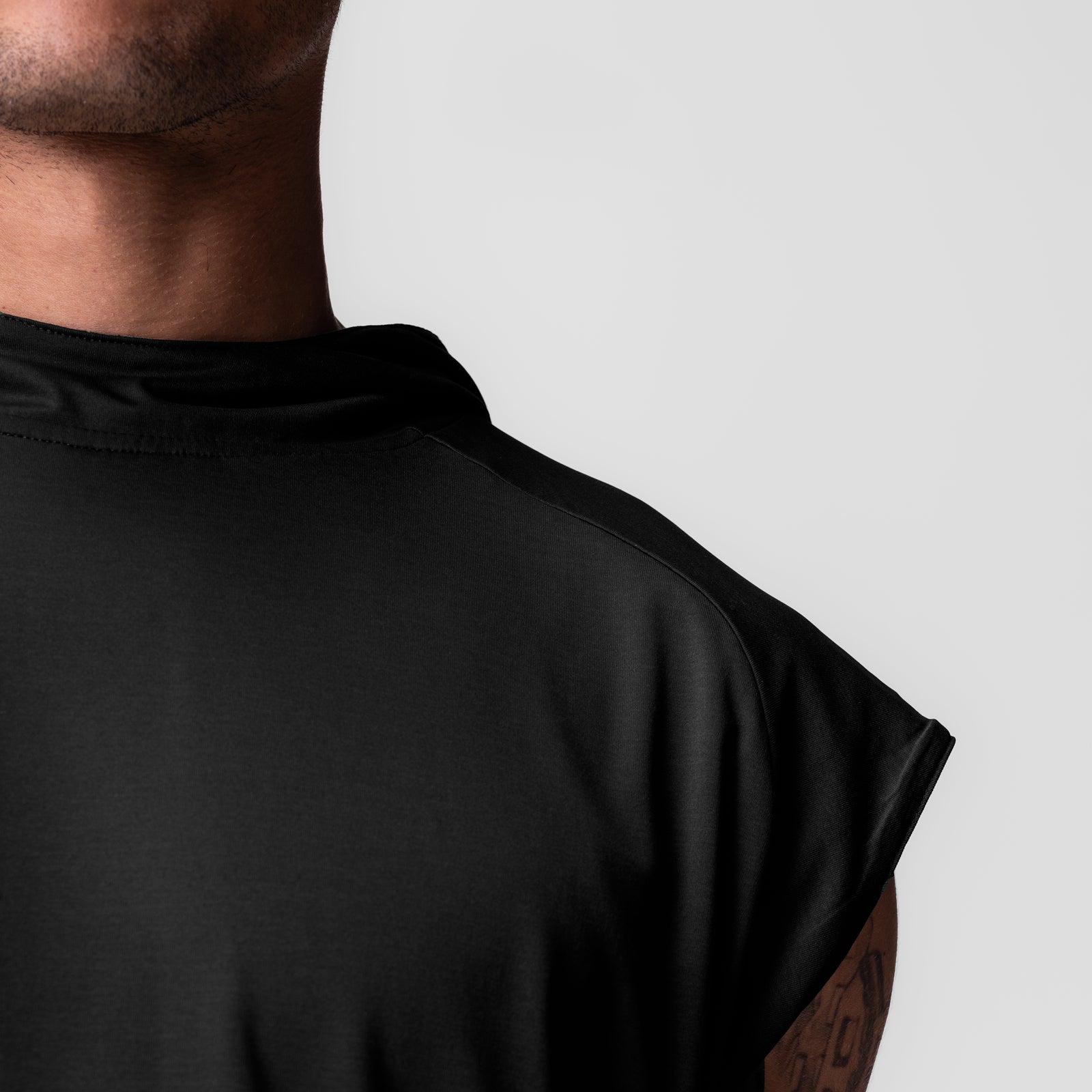 Black reversible 2-in-1 cutoff hoodie worn by model, shoulder detail view