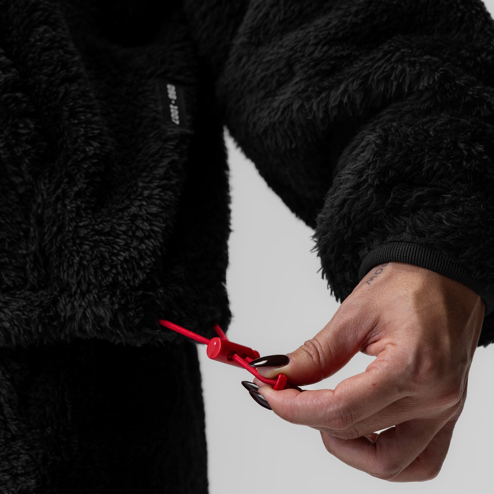 Women's Sherpa Recovery 1/2 Zip in black held in hand, showing red zipper detail
