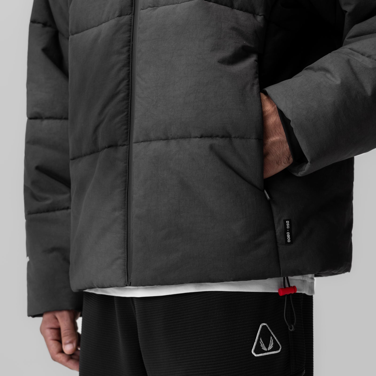 Black PrimaLoft puffer jacket worn by model, front detail view showing quilted design and hand pocket