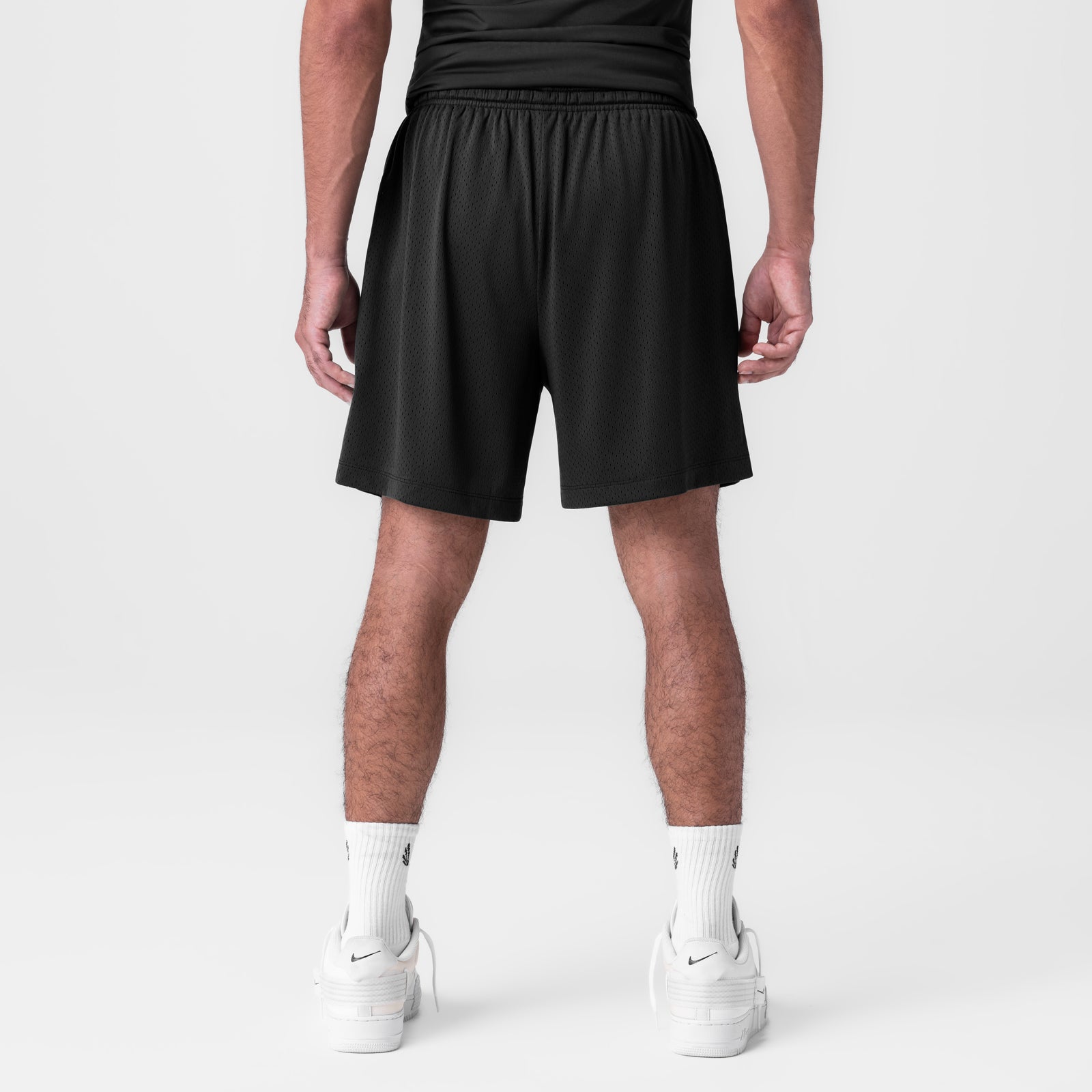 Black reversible 2-in-1 shorts on model, back view, worn with white socks and sneakers