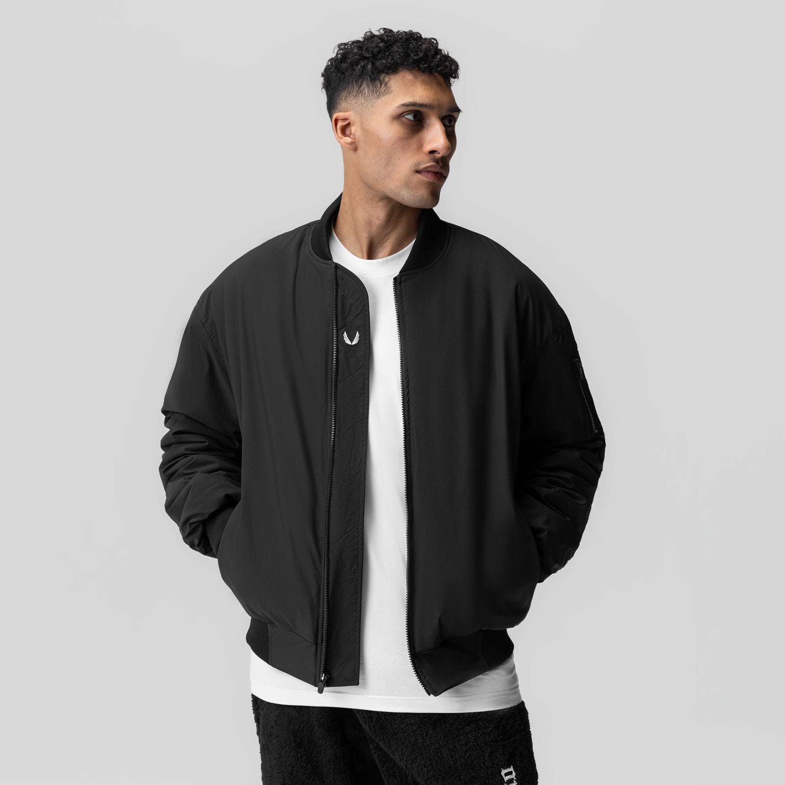 Black sherpa-lined insulated bomber jacket worn open over white tee, front view