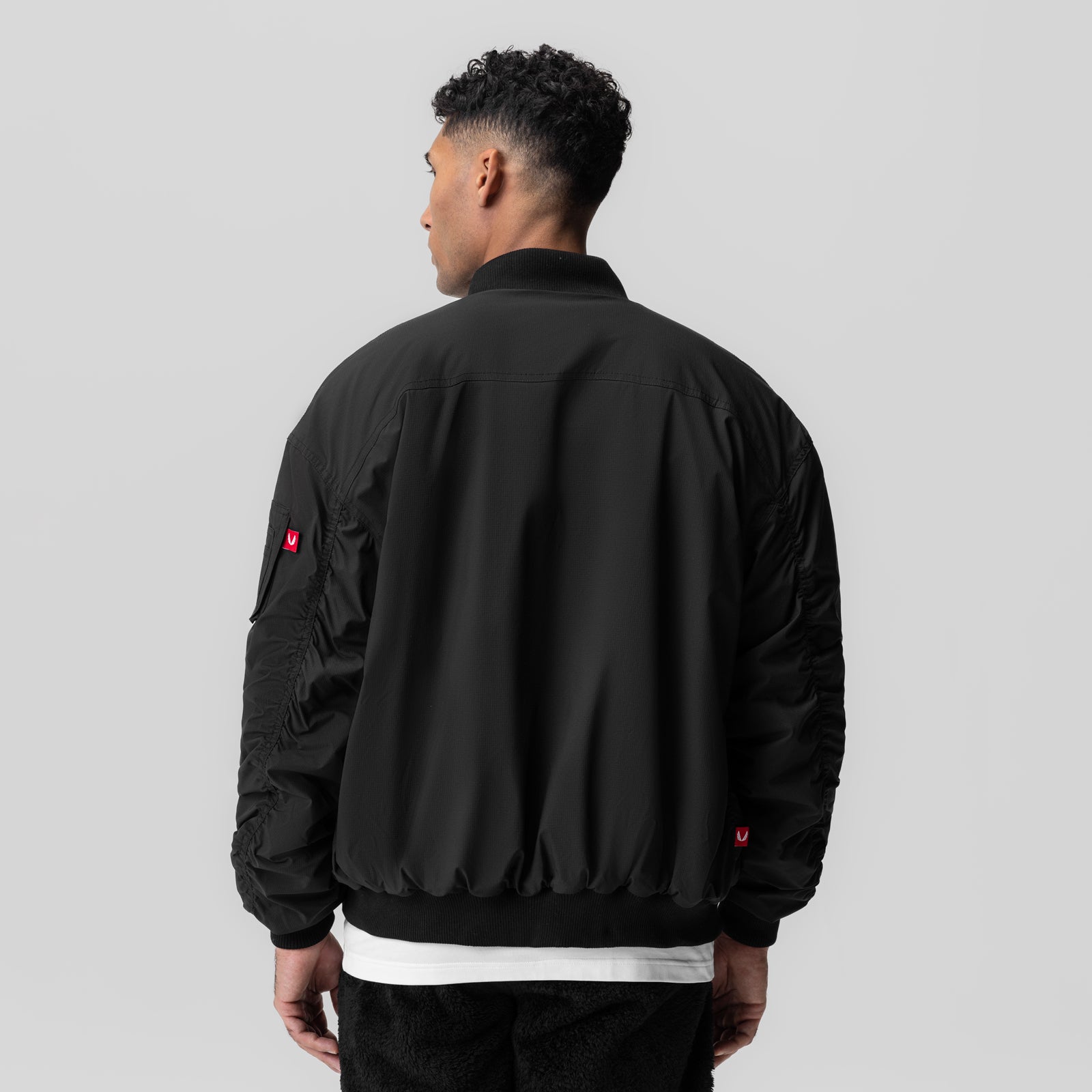 Black sherpa-lined insulated bomber jacket worn by model, back view