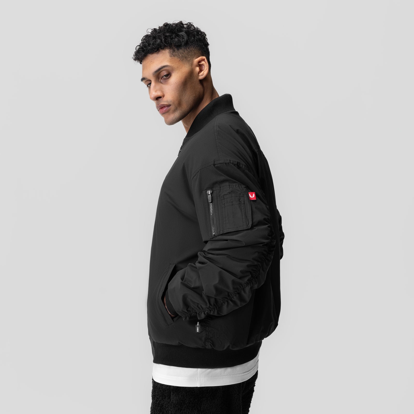 Black sherpa-lined insulated bomber jacket worn by model, side profile view