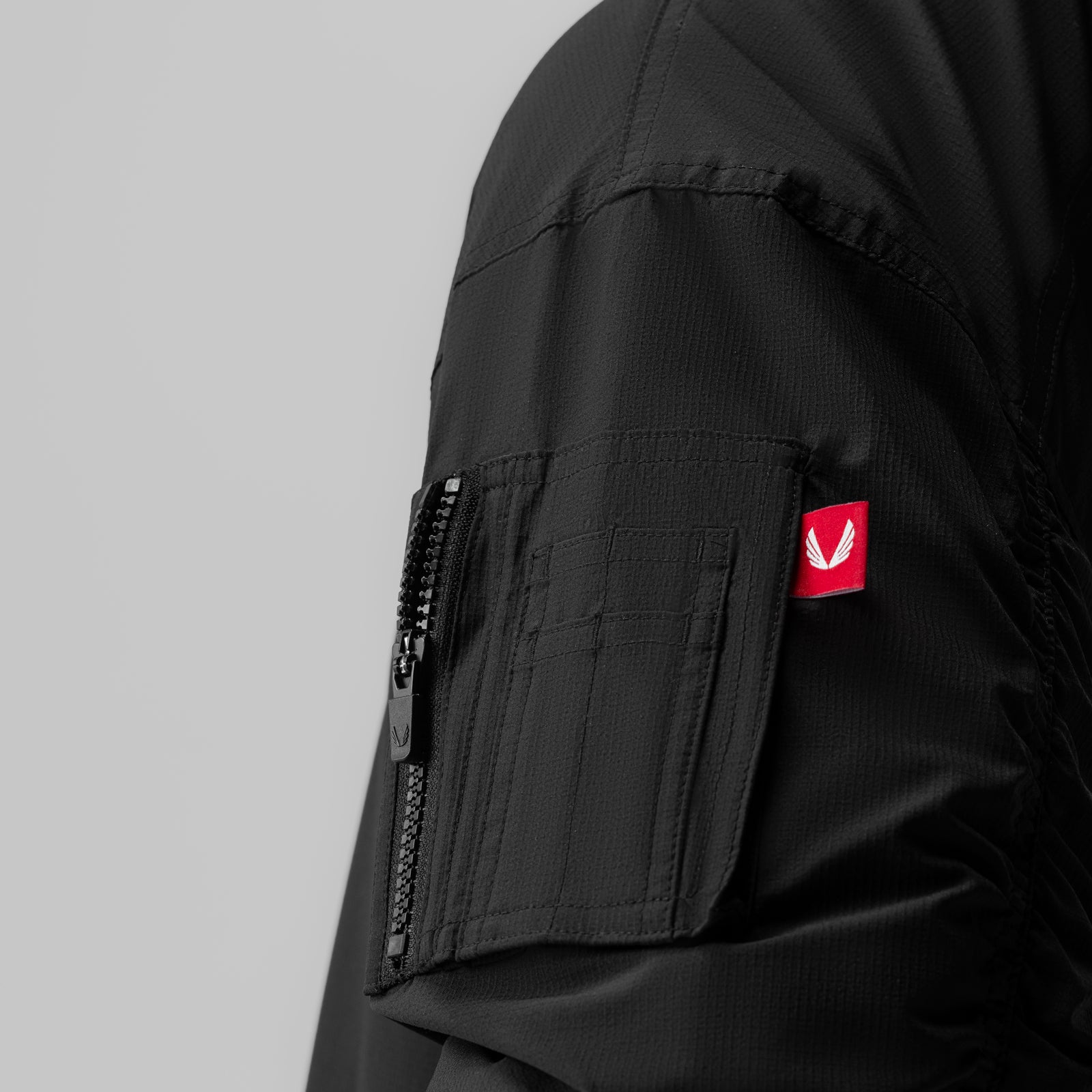 Black sherpa-lined insulated bomber jacket on model, sleeve detail with red logo patch