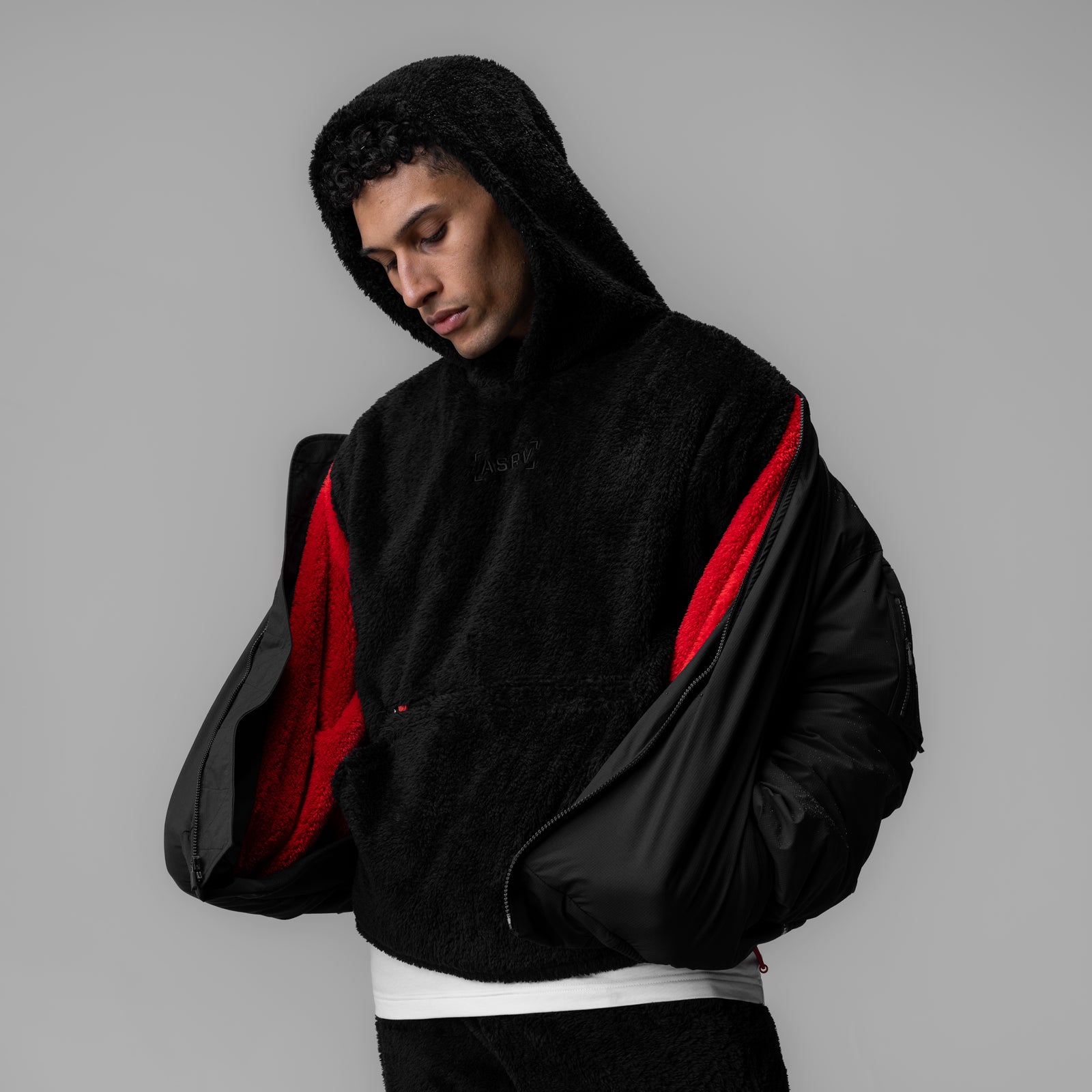 Sherpa-lined insulated bomber jacket in black with red lining, worn by model looking down