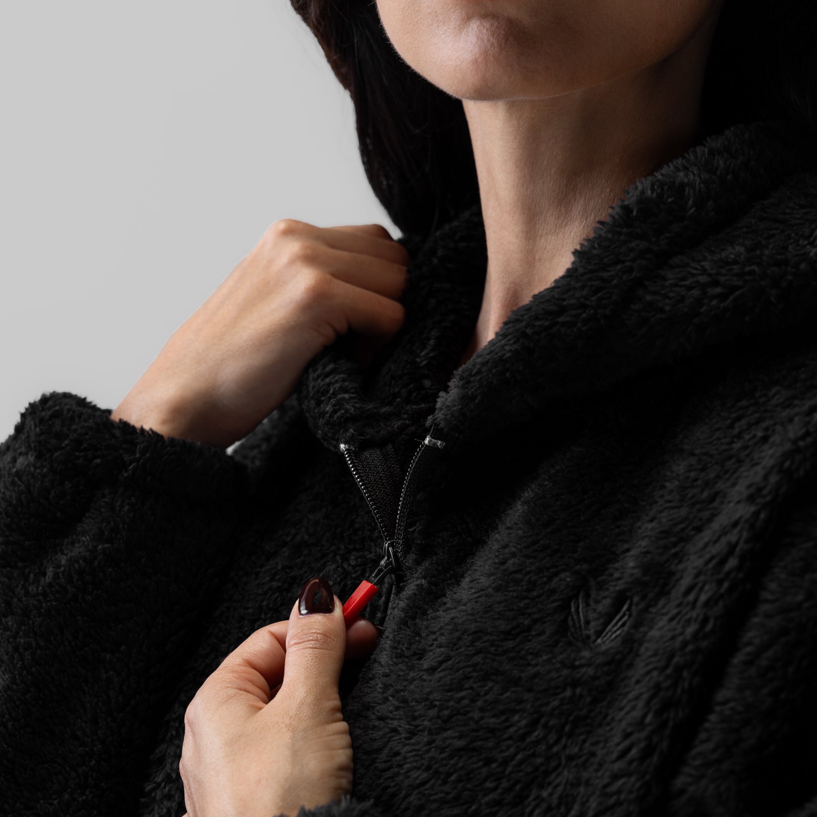 Women's Sherpa Recovery Full Zip Hoodie in black, worn with model holding zipper detail