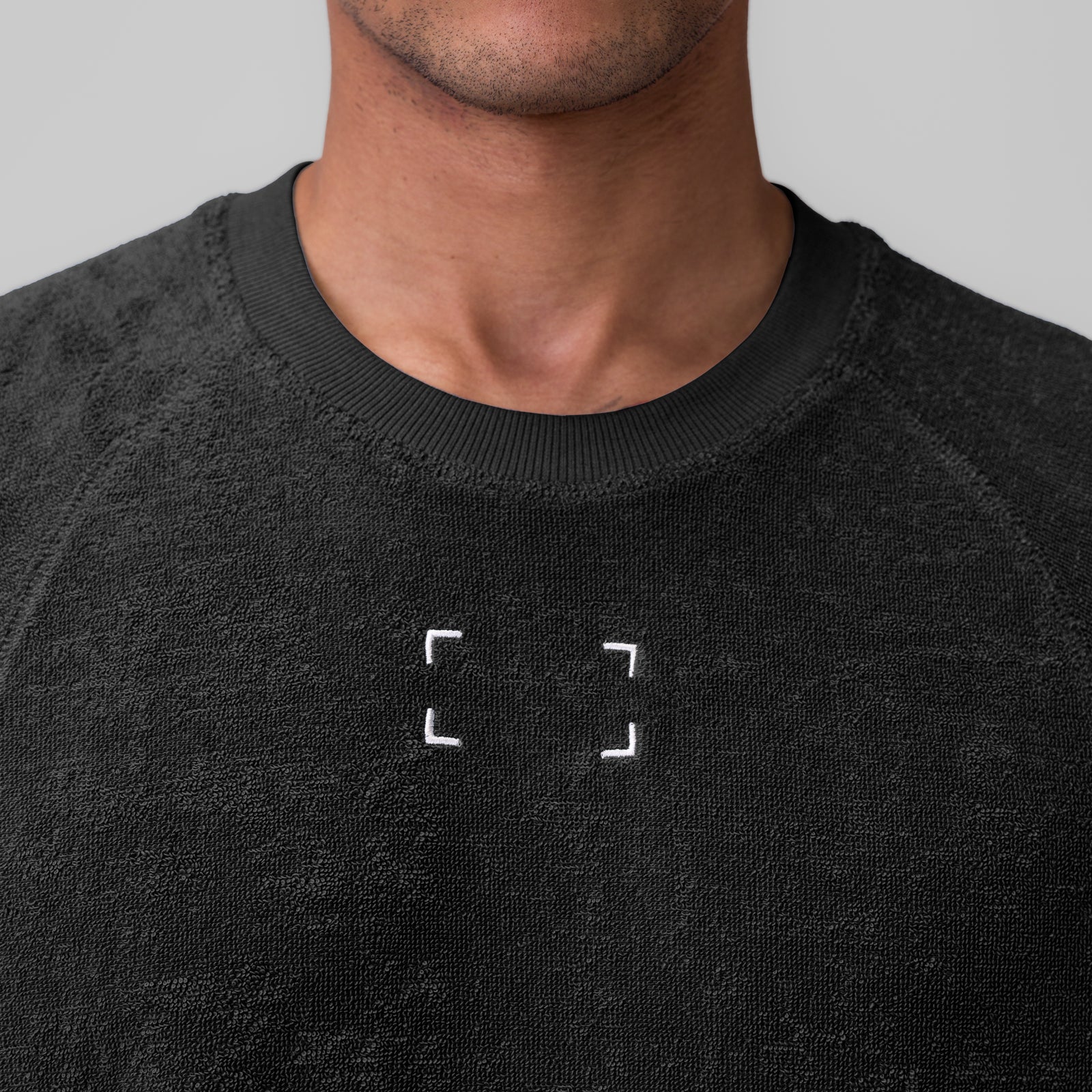 Black towel terry cutoff sweatshirt on model, front view with chest graphic detail