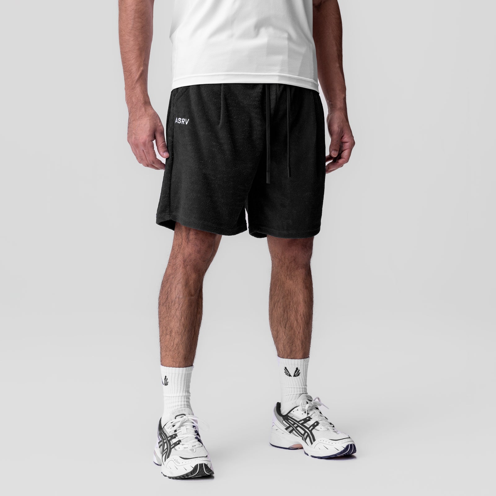 Black towel terry relaxed shorts worn by model with white tee and white sneakers, front view