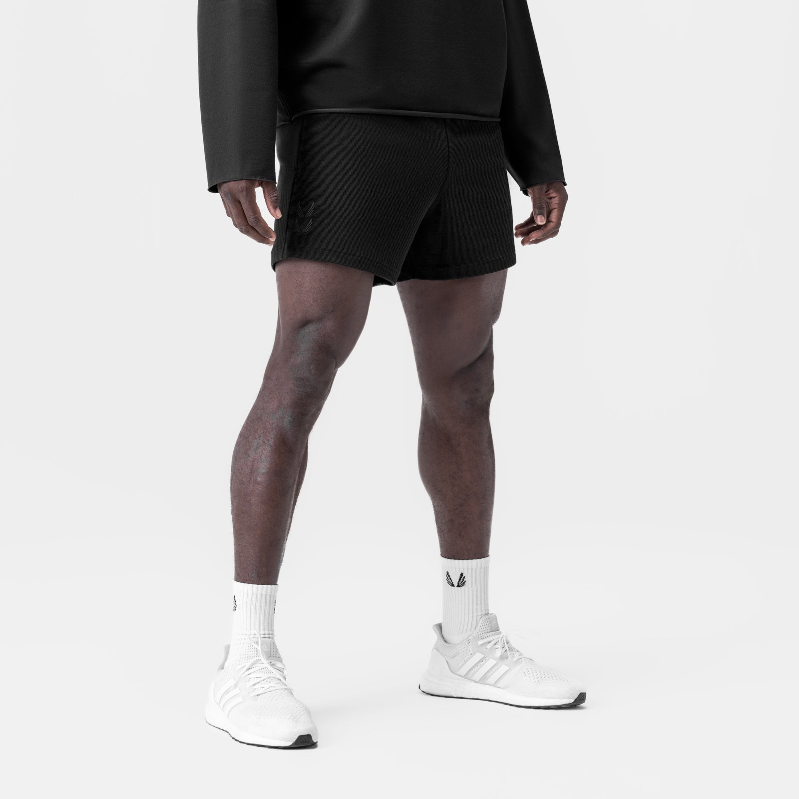 Black waffle knit sweat shorts worn with white socks and sneakers, front view