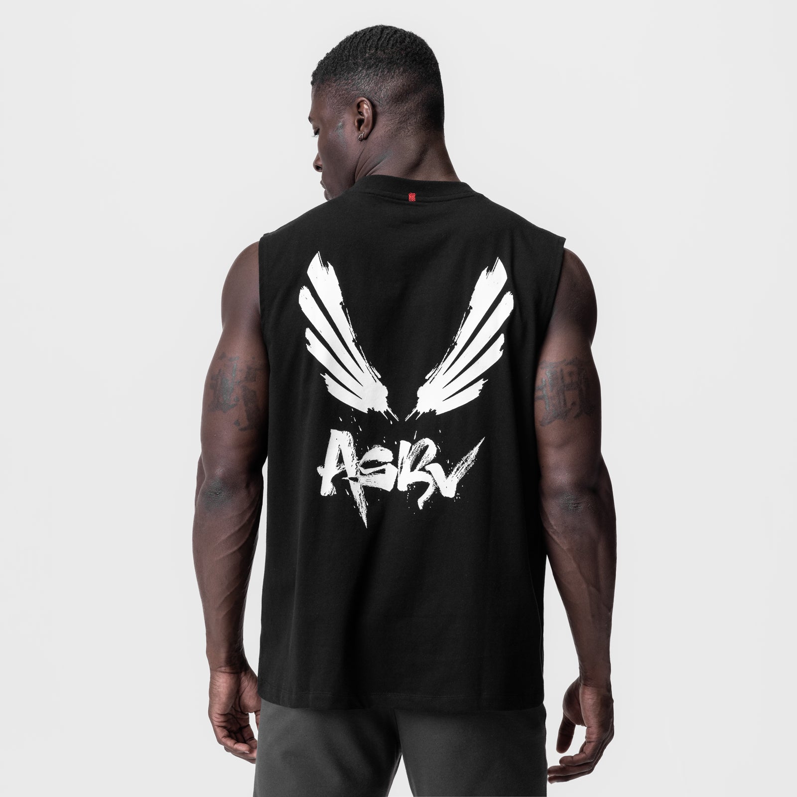 Black Tech Essential Relaxed Cutoff tank top with white brush wings graphic, back view on model