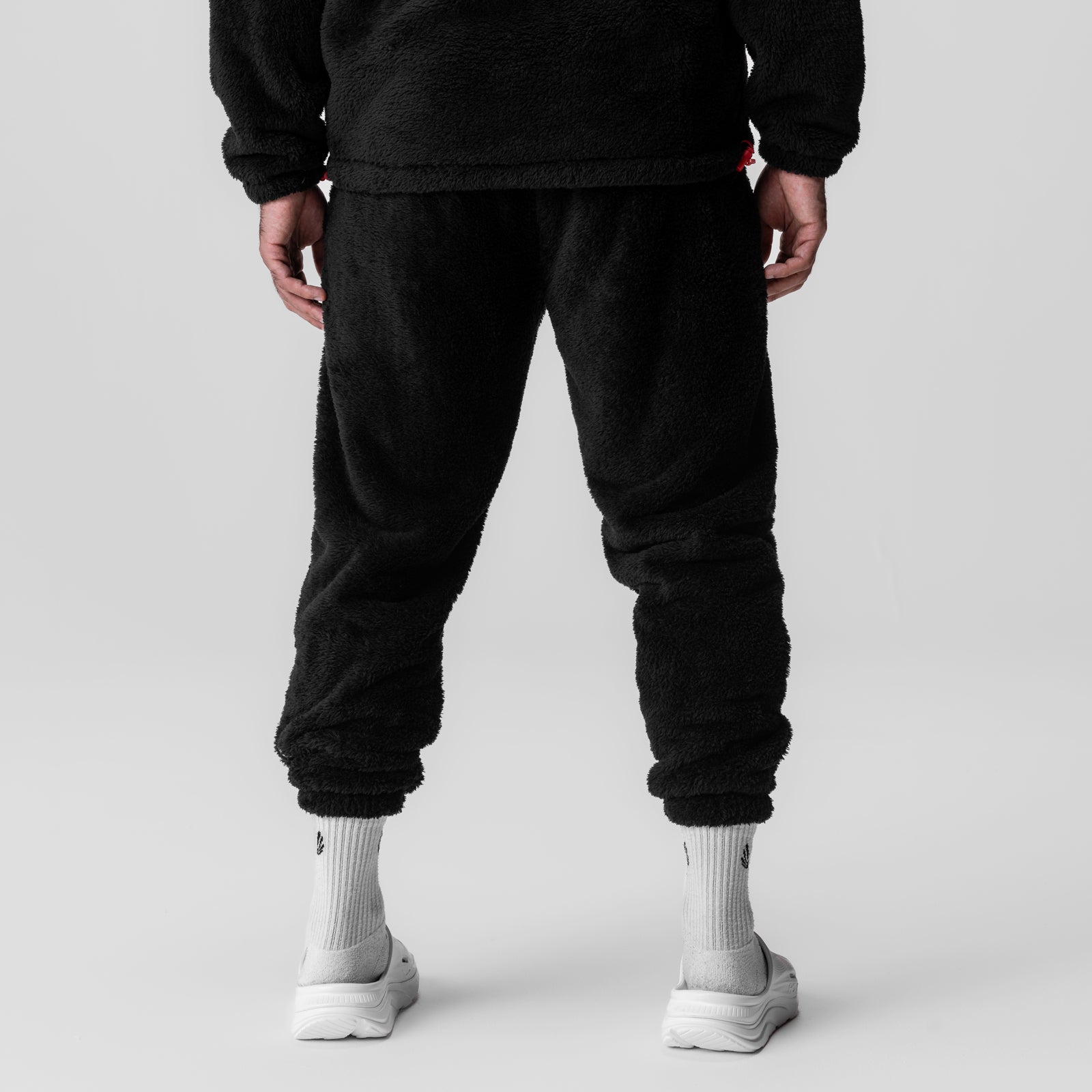Sherpa Recovery Sweats in black worn by model, back view with white socks and sneakers