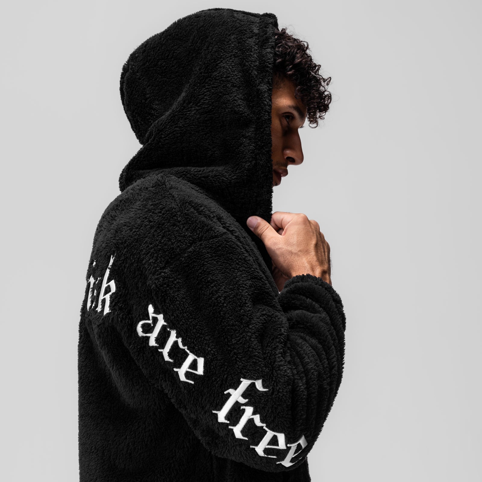 Black Sherpa Recovery Full Zip Hoodie worn by model in profile view, showing white embroidered text on sleeve