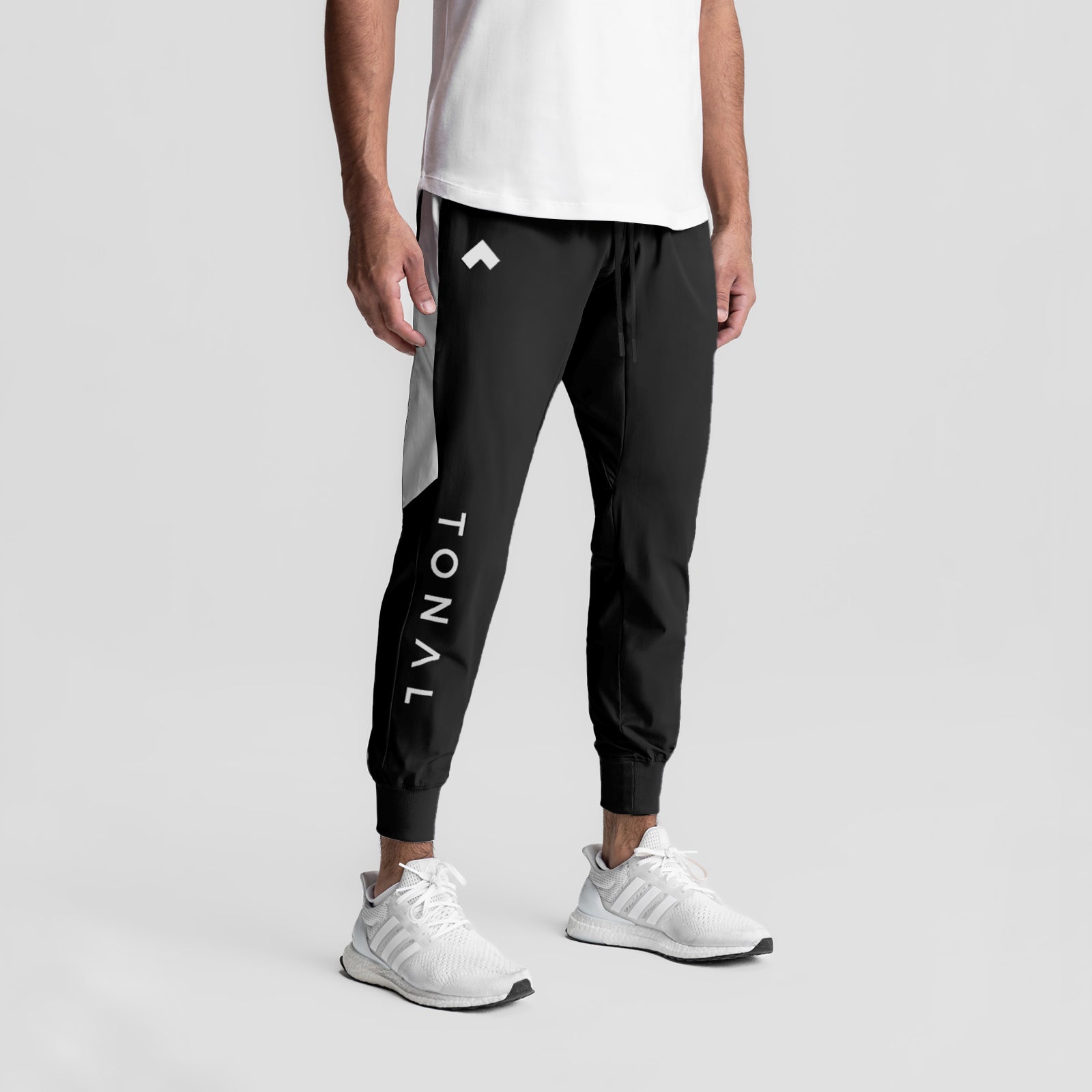 Black Tetra-Lite cuffed training jogger worn by model with white sneakers, front view