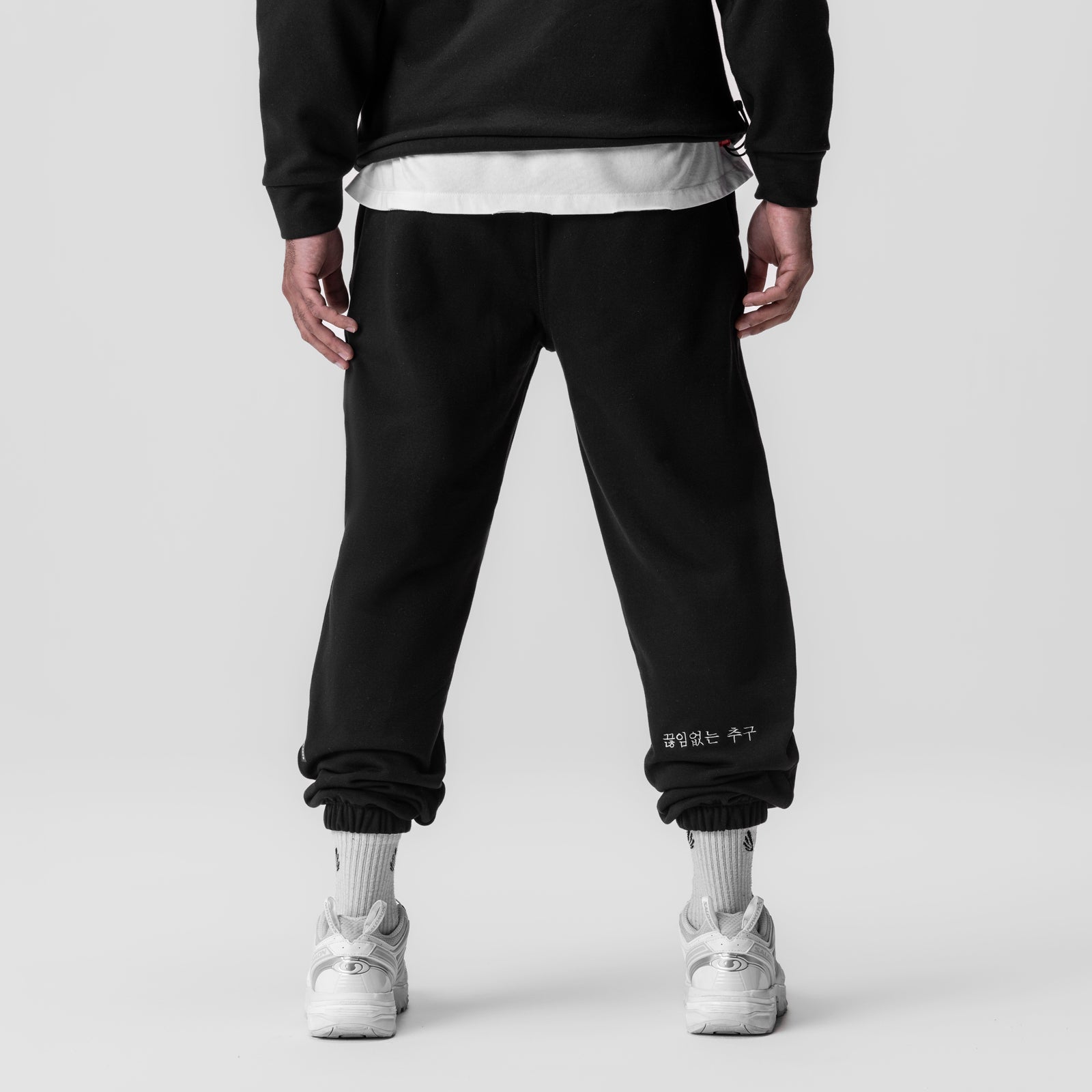 Black Tech-Terry oversized sweatpants on model, back view with white socks and sneakers