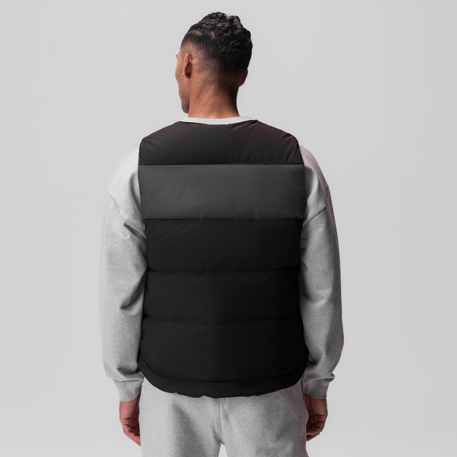 Black ripstop insulated puffer gilet worn over gray long-sleeve shirt, back view
