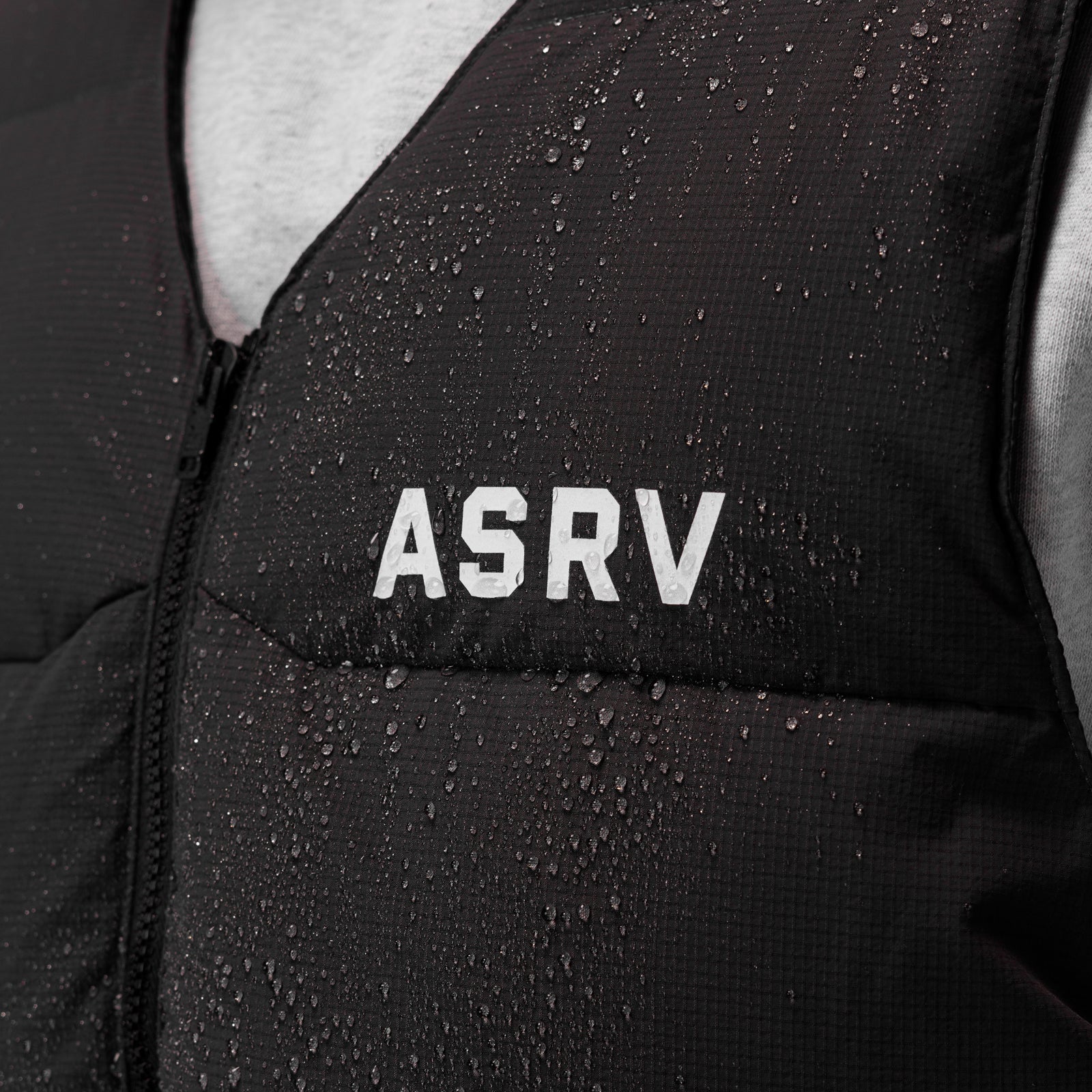 Black ripstop insulated puffer gilet being worn, water droplets visible on fabric, front view detail