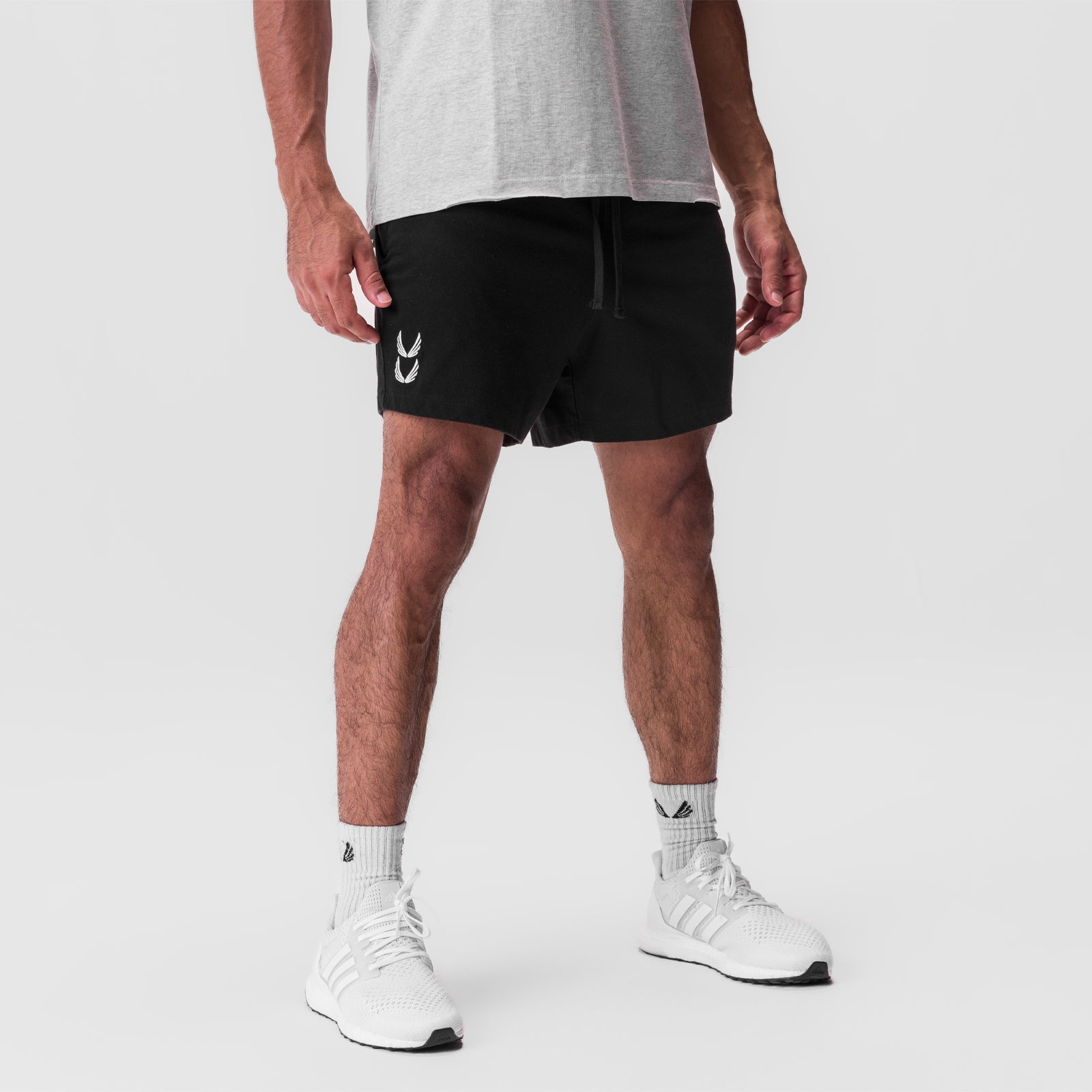 Tech Essential™ Sweat Short in black, worn by model with white sneakers and socks