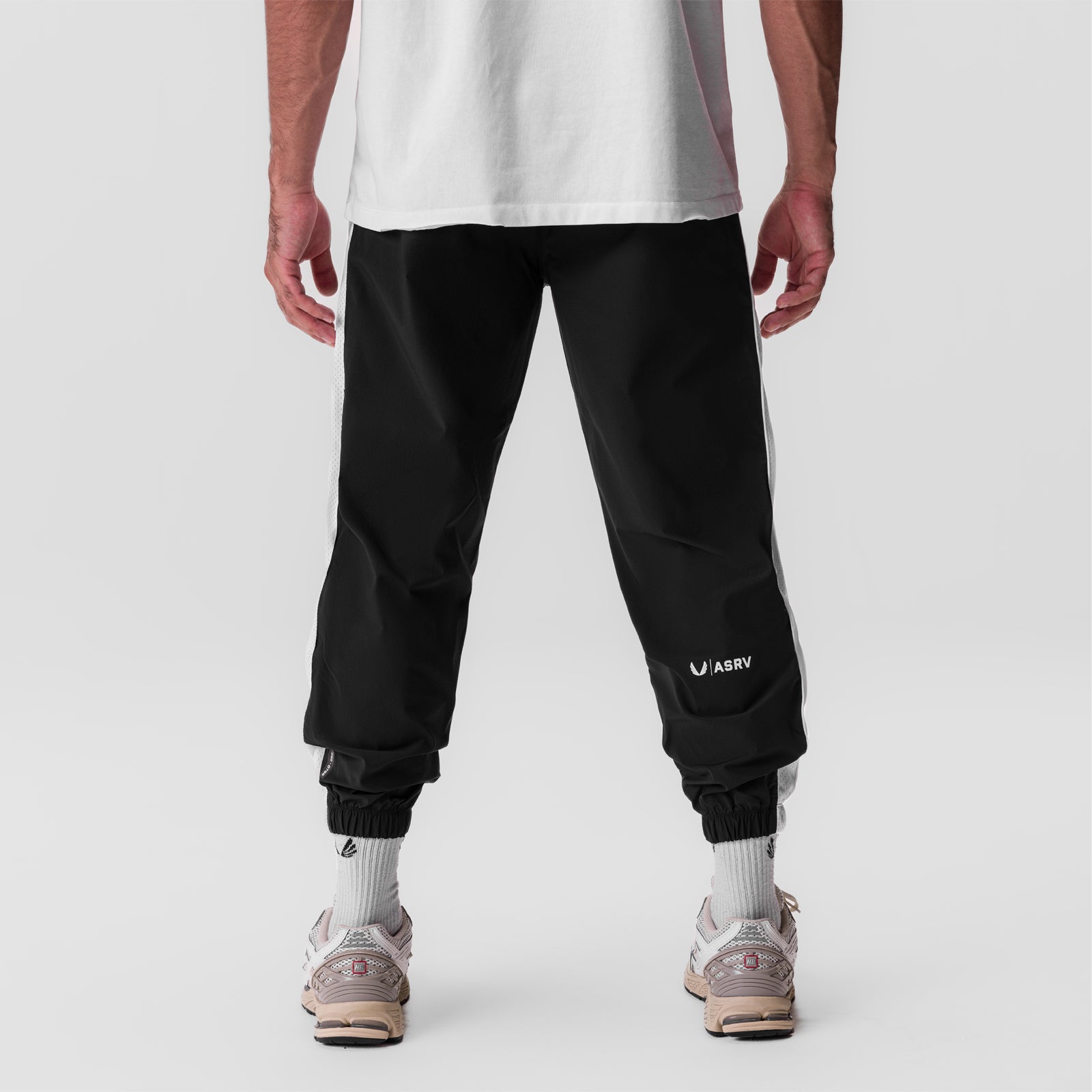Black ripstop oversized track pant worn by model, back view with white socks and sneakers