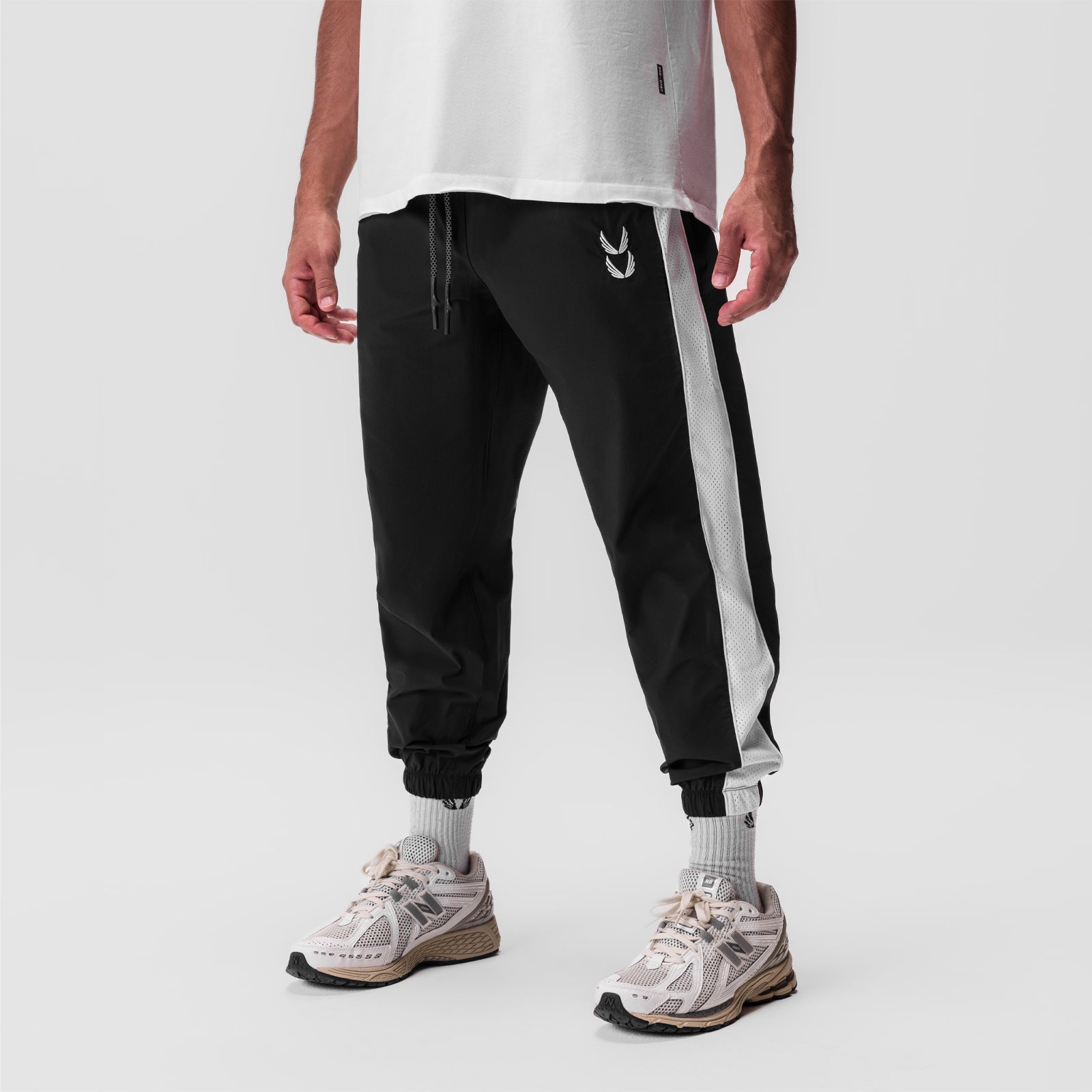 Black ripstop oversized track pant on model, paired with white socks and sneakers, front view