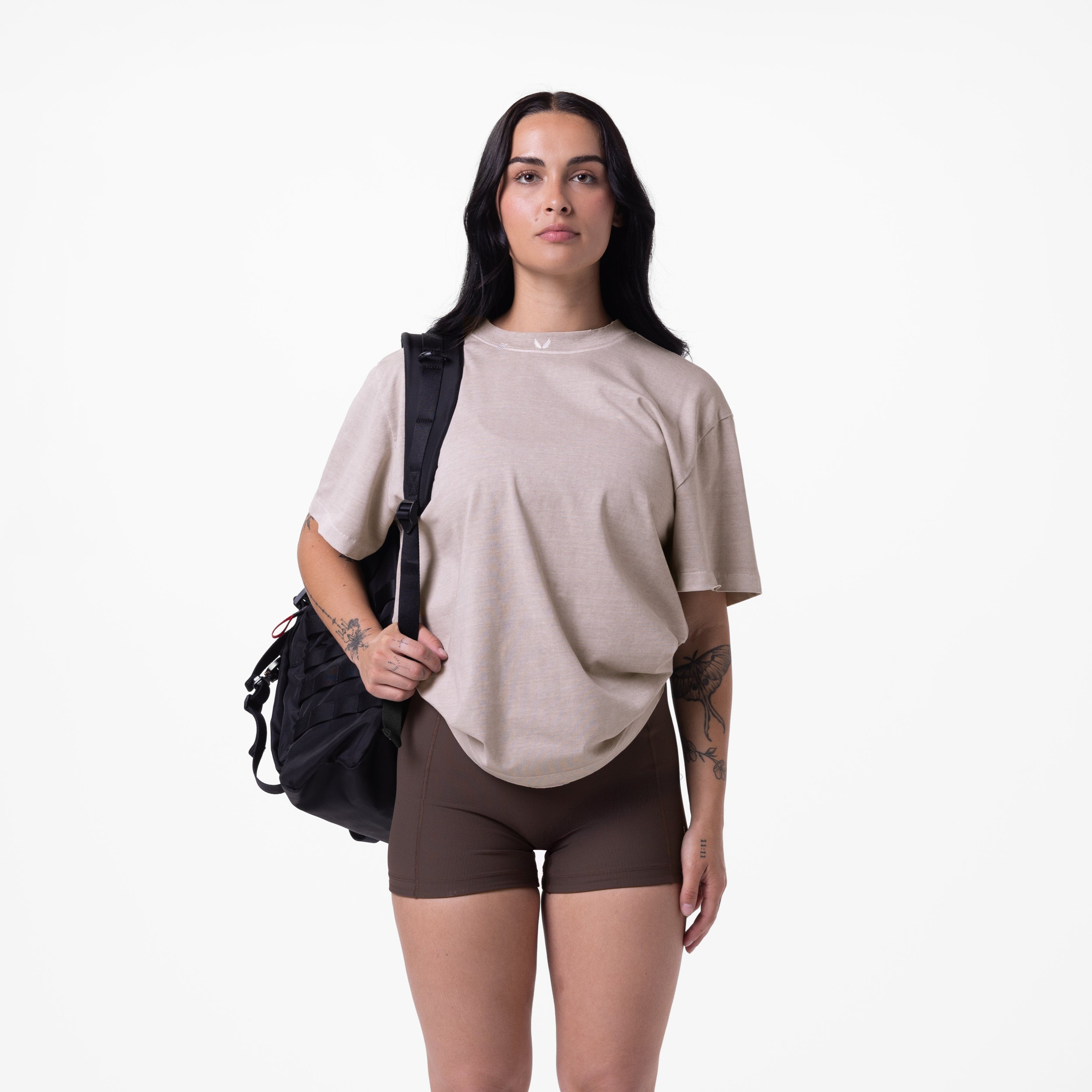 Tech Essential Relaxed Tee in faded chai worn with brown shorts and black backpack, front view