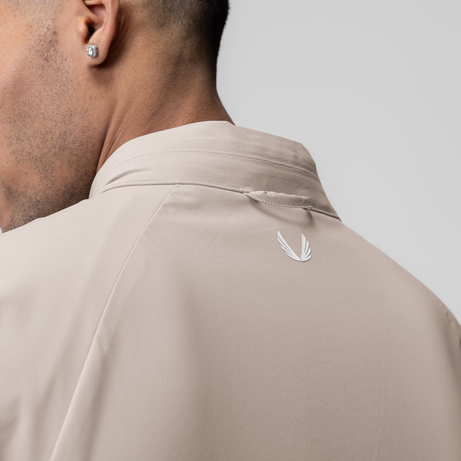 Aerotex Weather-Ready Bonded Windbreaker in chai, worn by model, back view showing feather logo