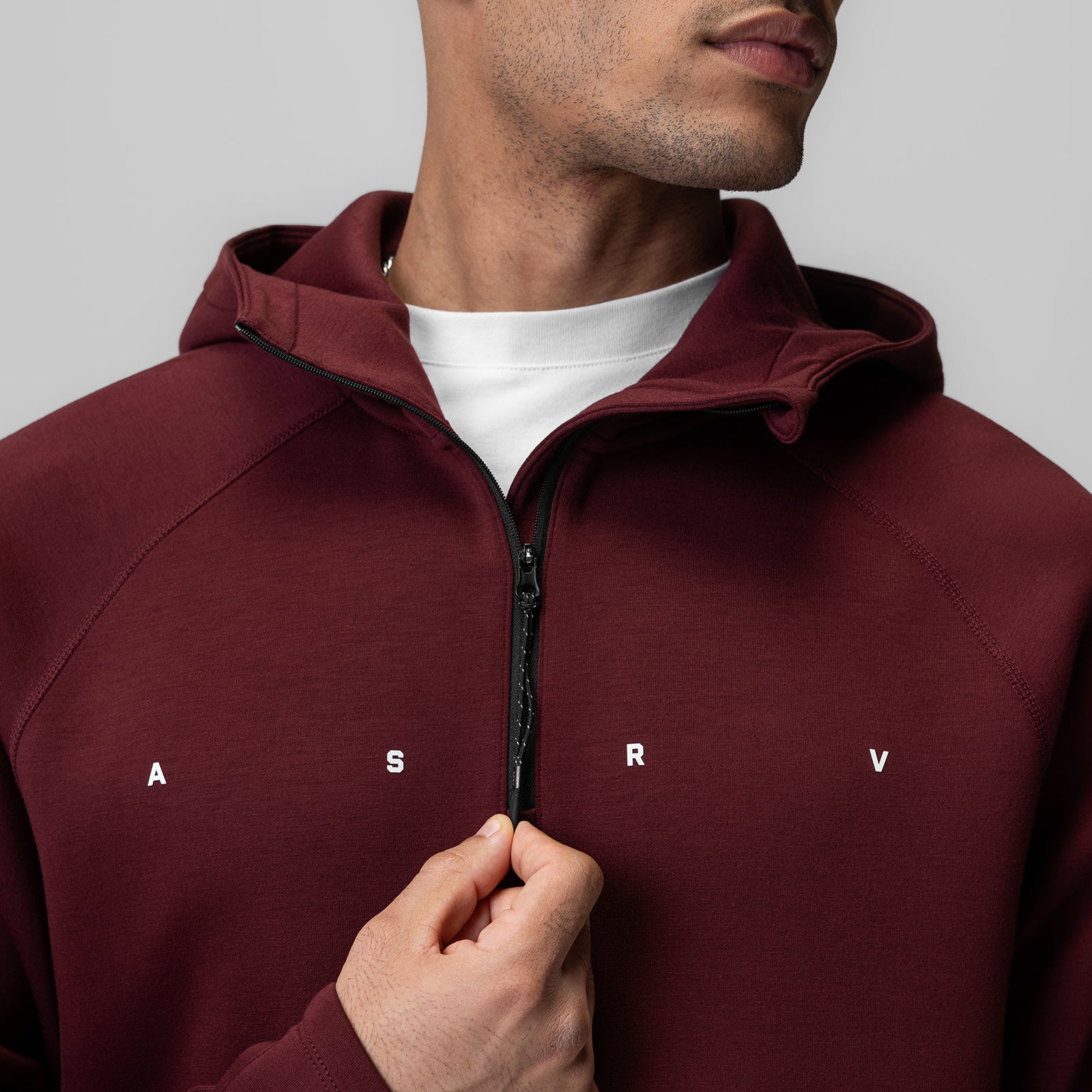 Dri-Core Zip Hoodie in crimson worn by model, front view with hand on zipper