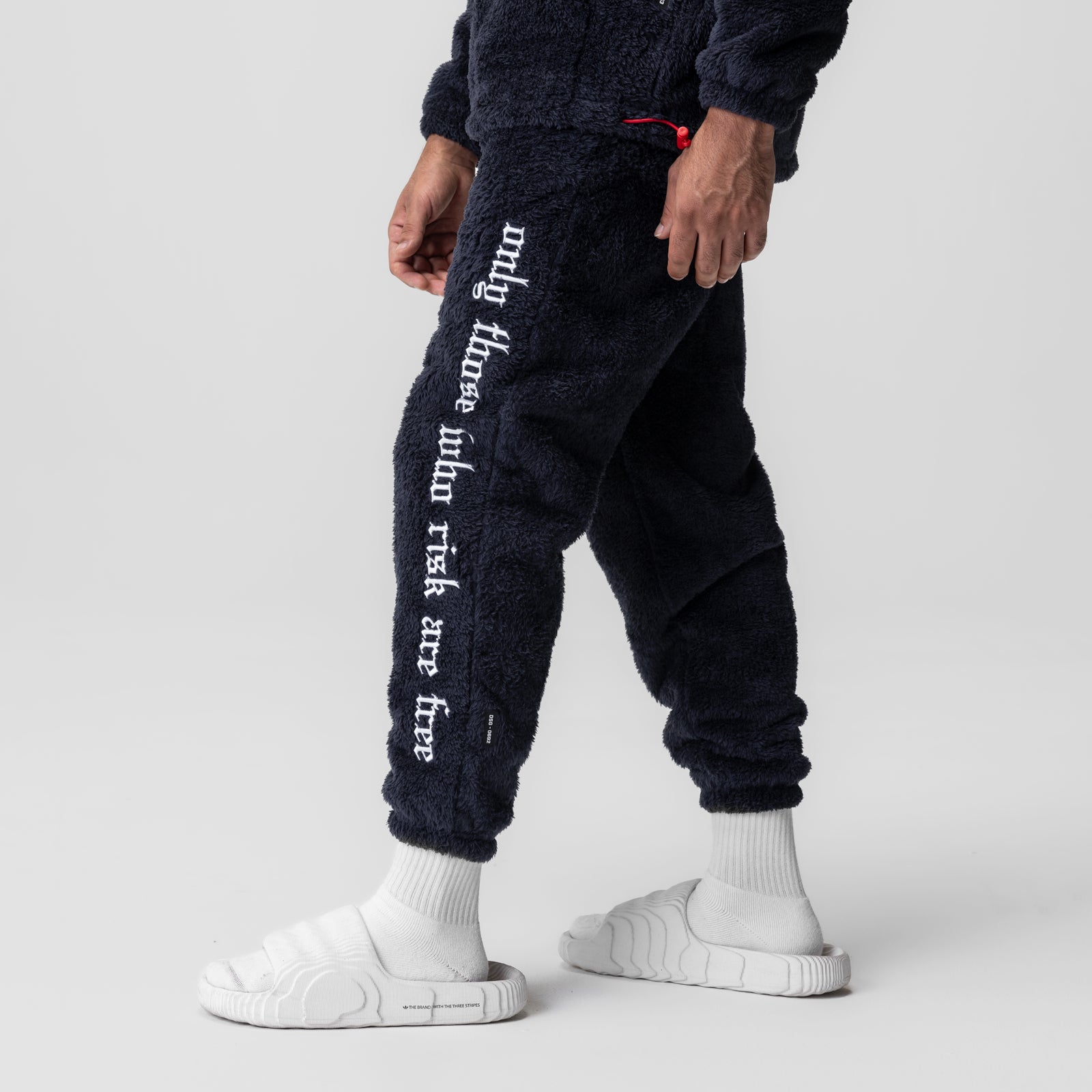 Sherpa Recovery Sweats in navy worn by model with white socks and slides, leg detail view
