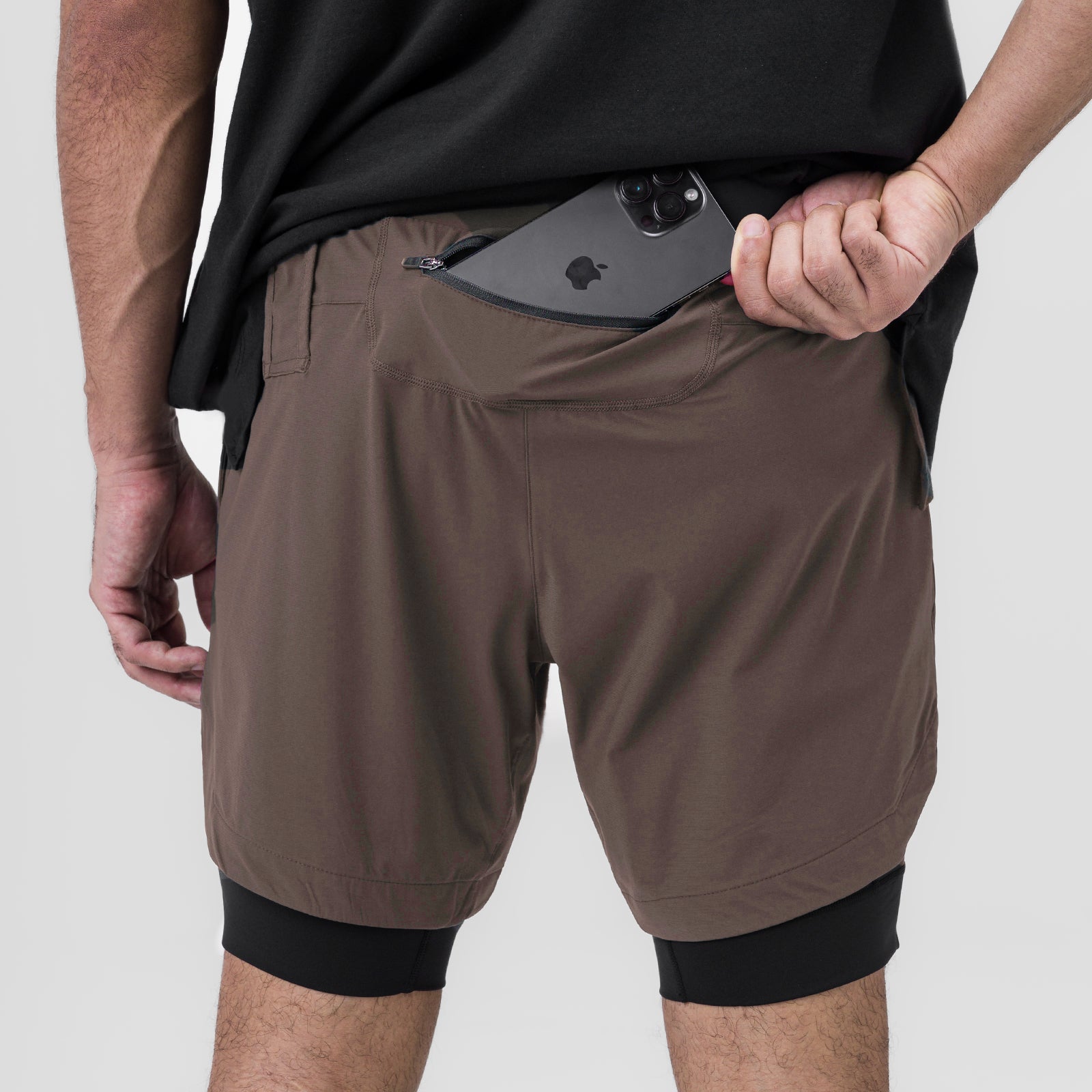 Tetra-Lite 7" Liner Short in Deep Taupe and Black, worn by model holding smartphone in front pocket