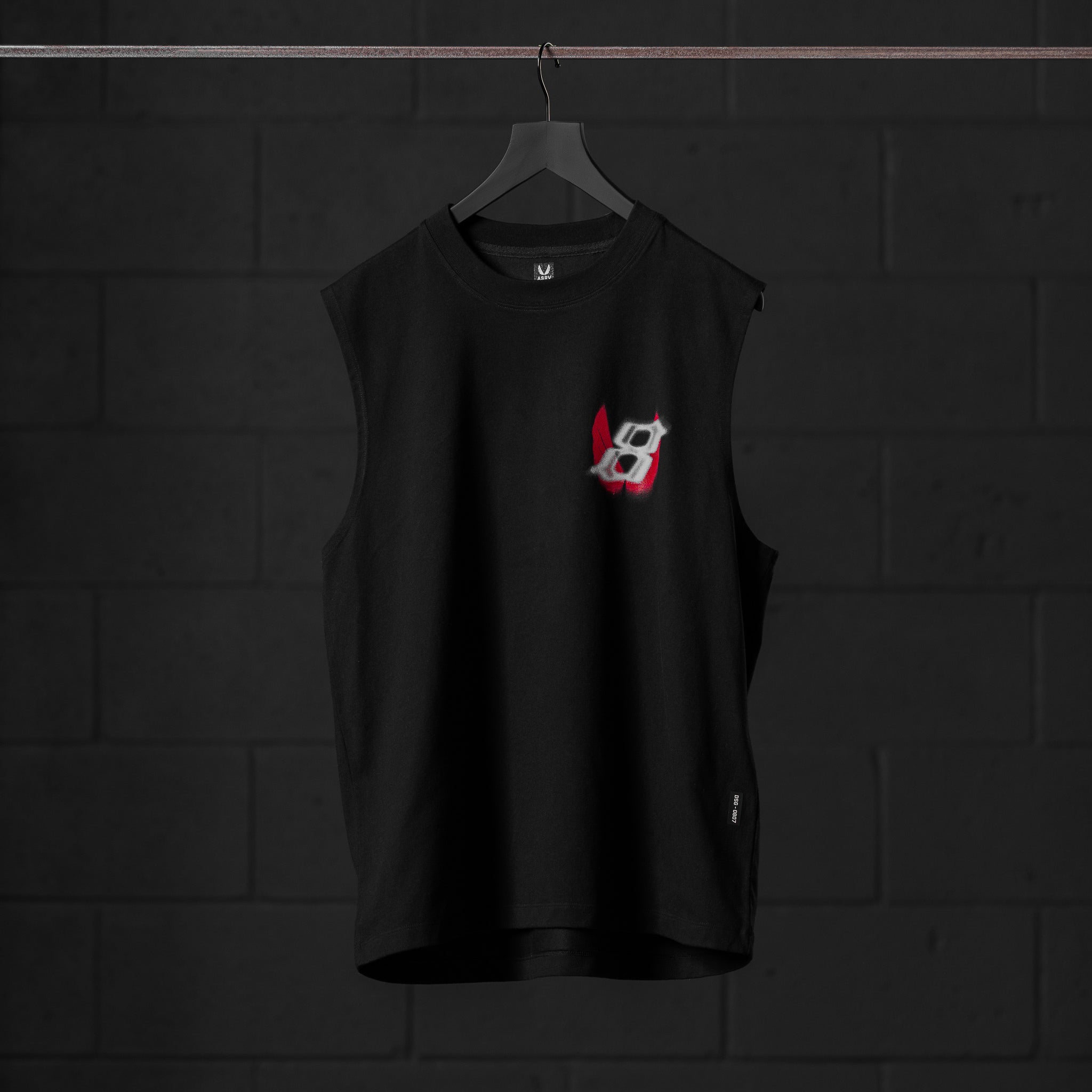 Black Tech Essential Relaxed Cutoff sleeveless tank on hanger, front view with red graphic