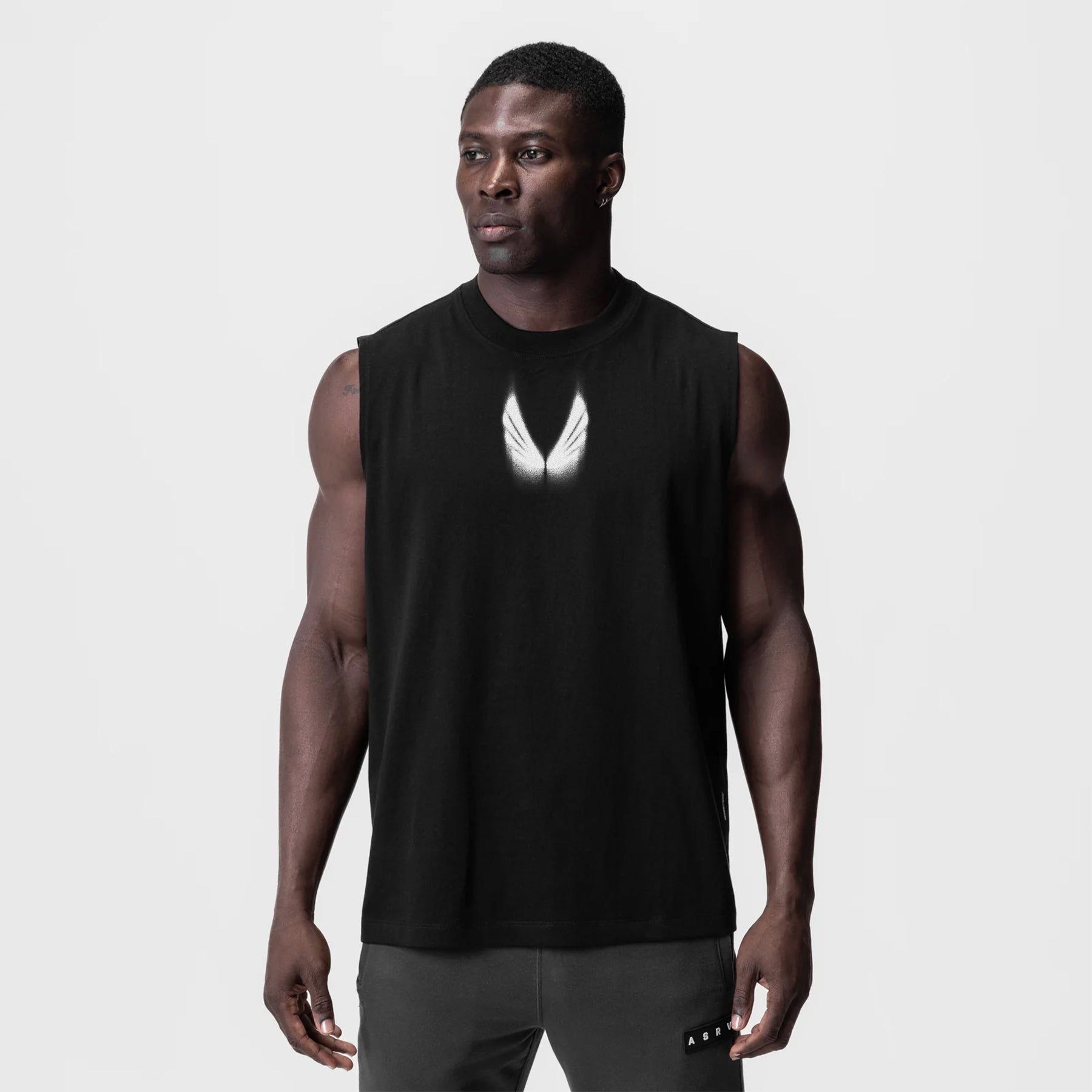 Black Tech Essential Relaxed Cutoff tank top with white motion blur logo, worn by model