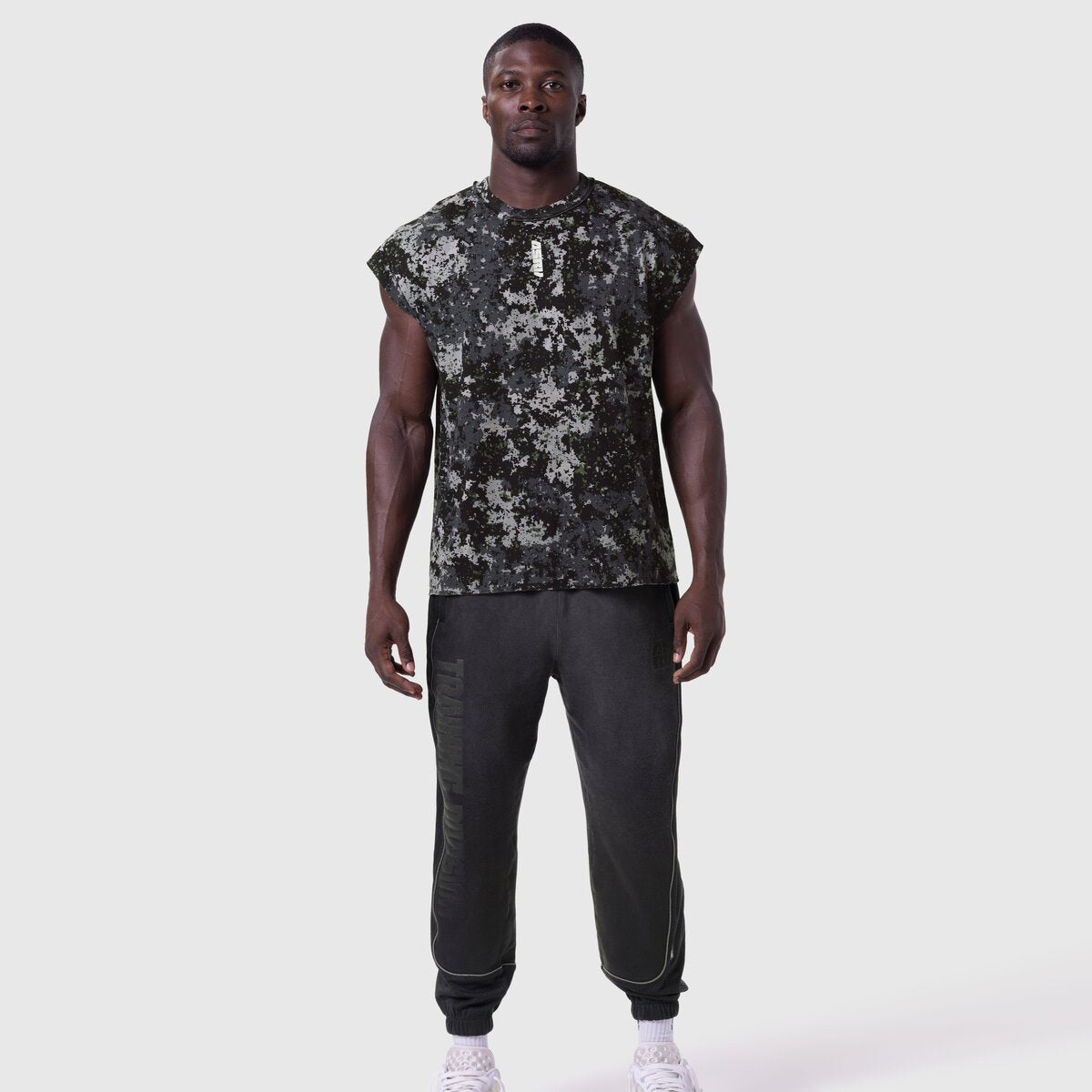 Tech Essential Cap Shoulder Cutoff in Pixel Camo worn with black joggers, front view