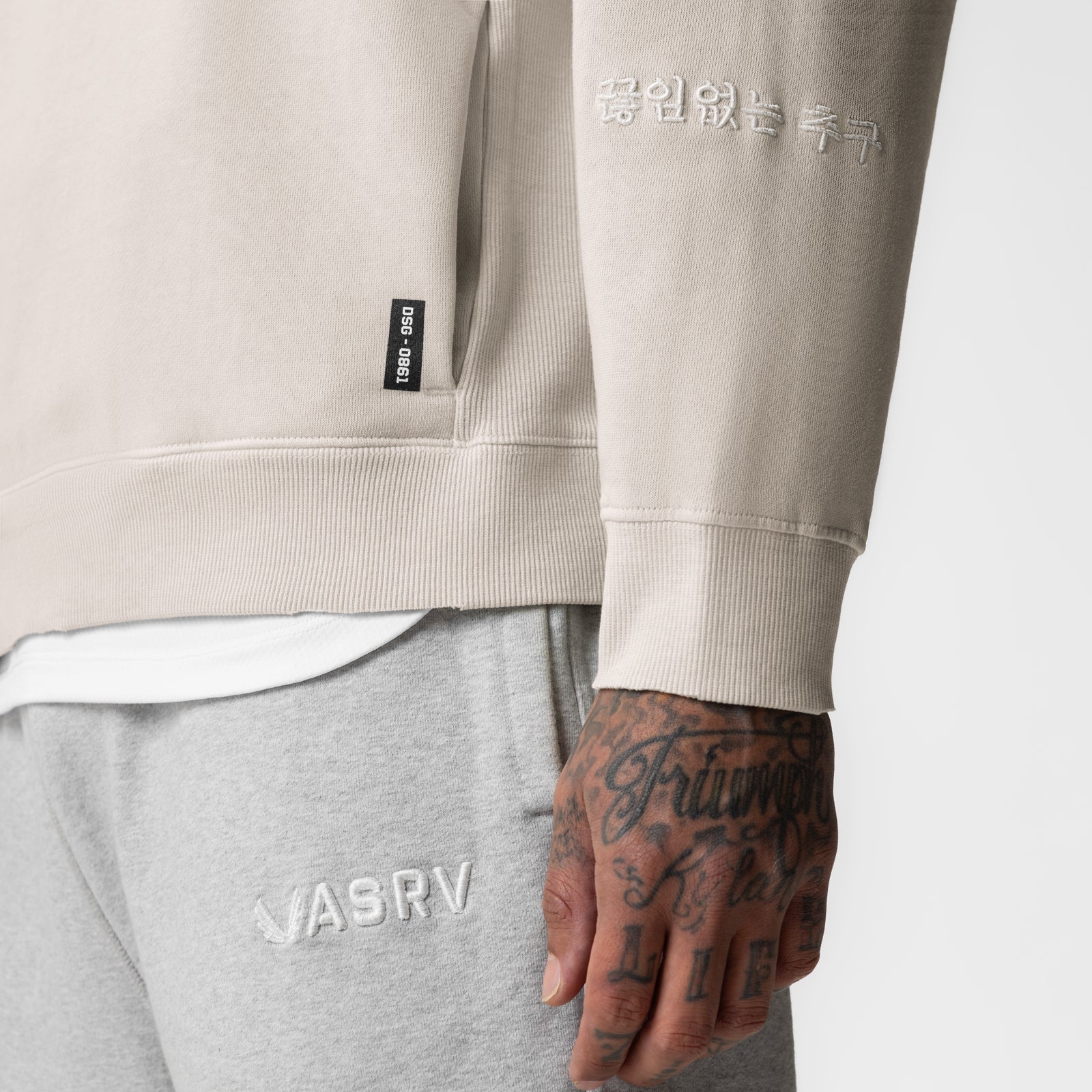 Tech Essential Distressed Crewneck in Faded Stone, worn with grey joggers, detail view