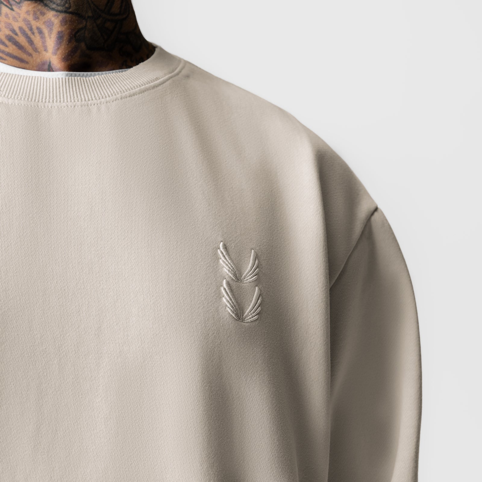 Tech Essential Distressed Crewneck in Faded Stone, worn by model showing chest embroidery detail