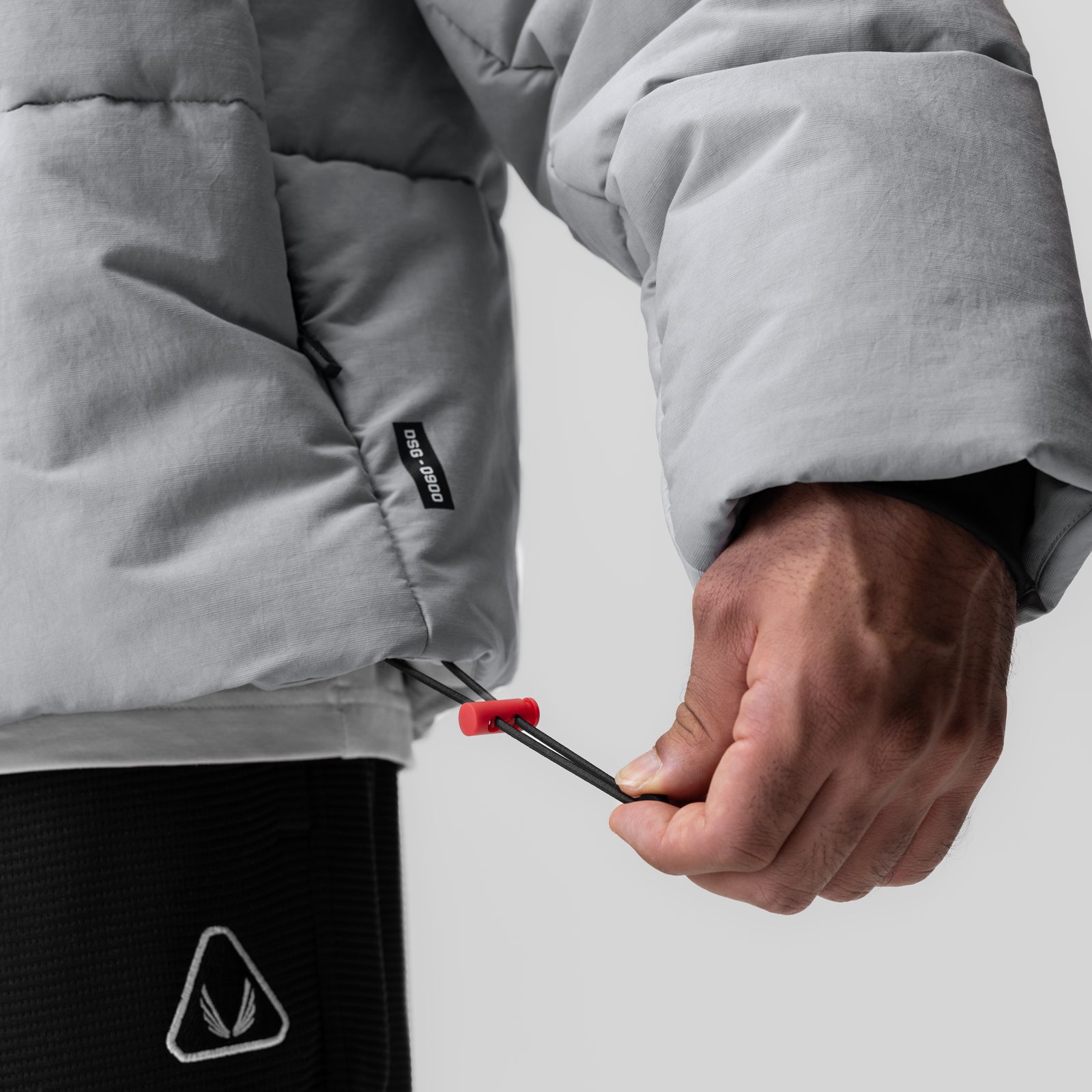 Grey PrimaLoft® puffer jacket worn by model, detail of drawstring and cuff